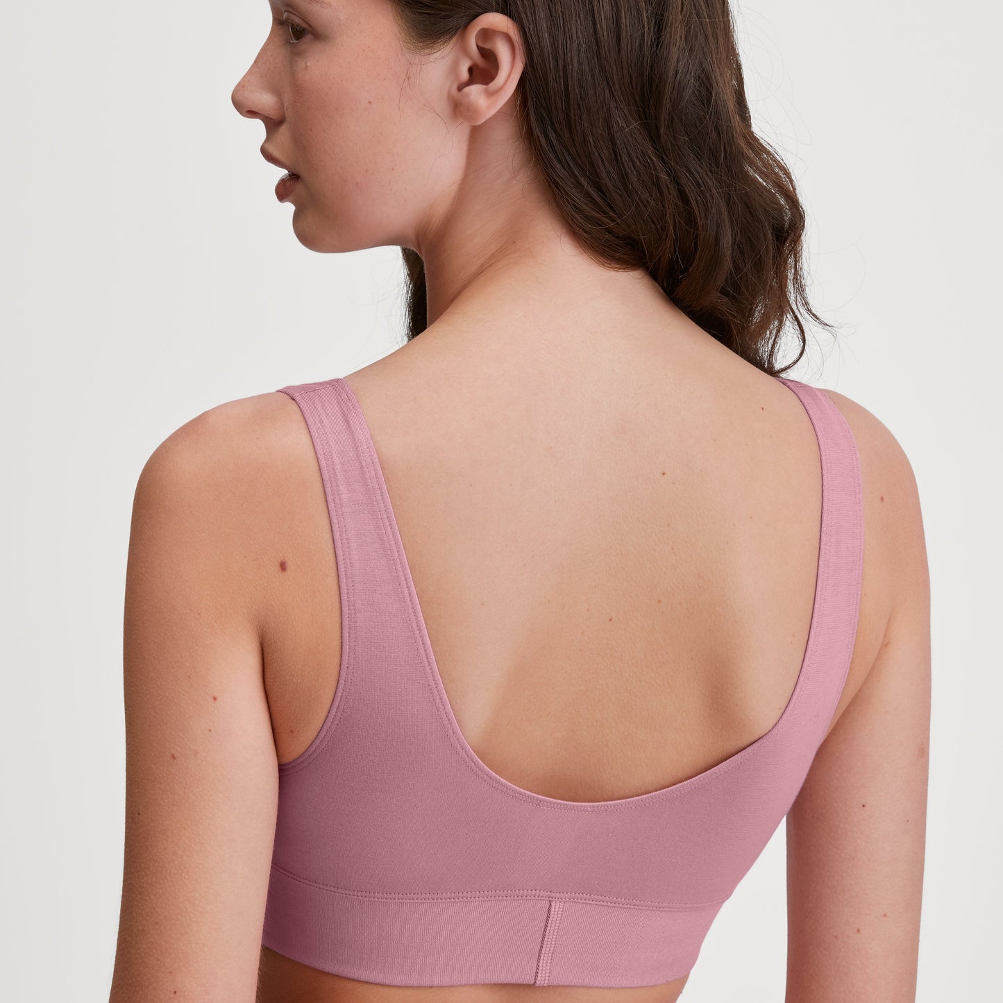 Woman wearing a pink sports bra against a white background