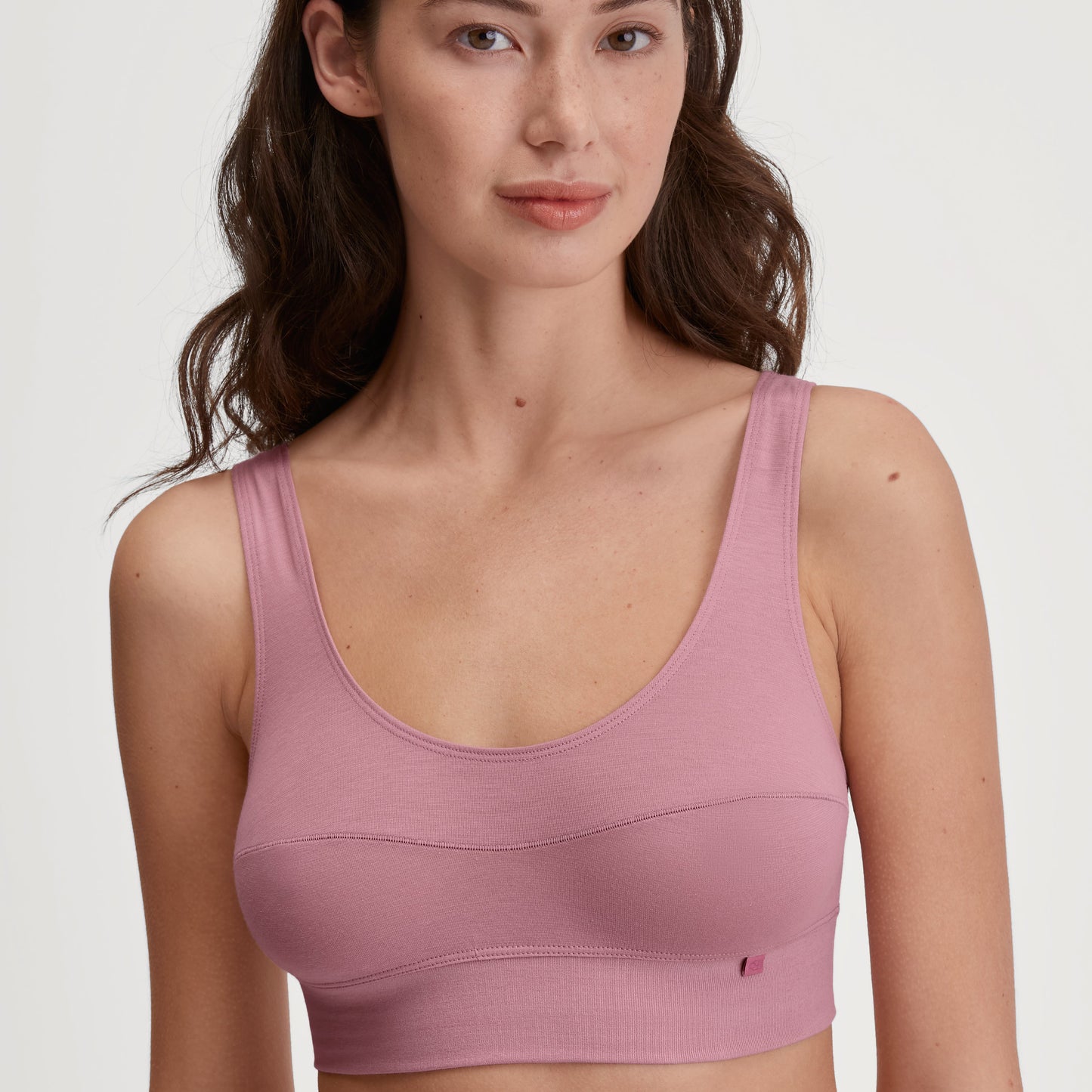 Woman wearing a pink sports bra against a plain background