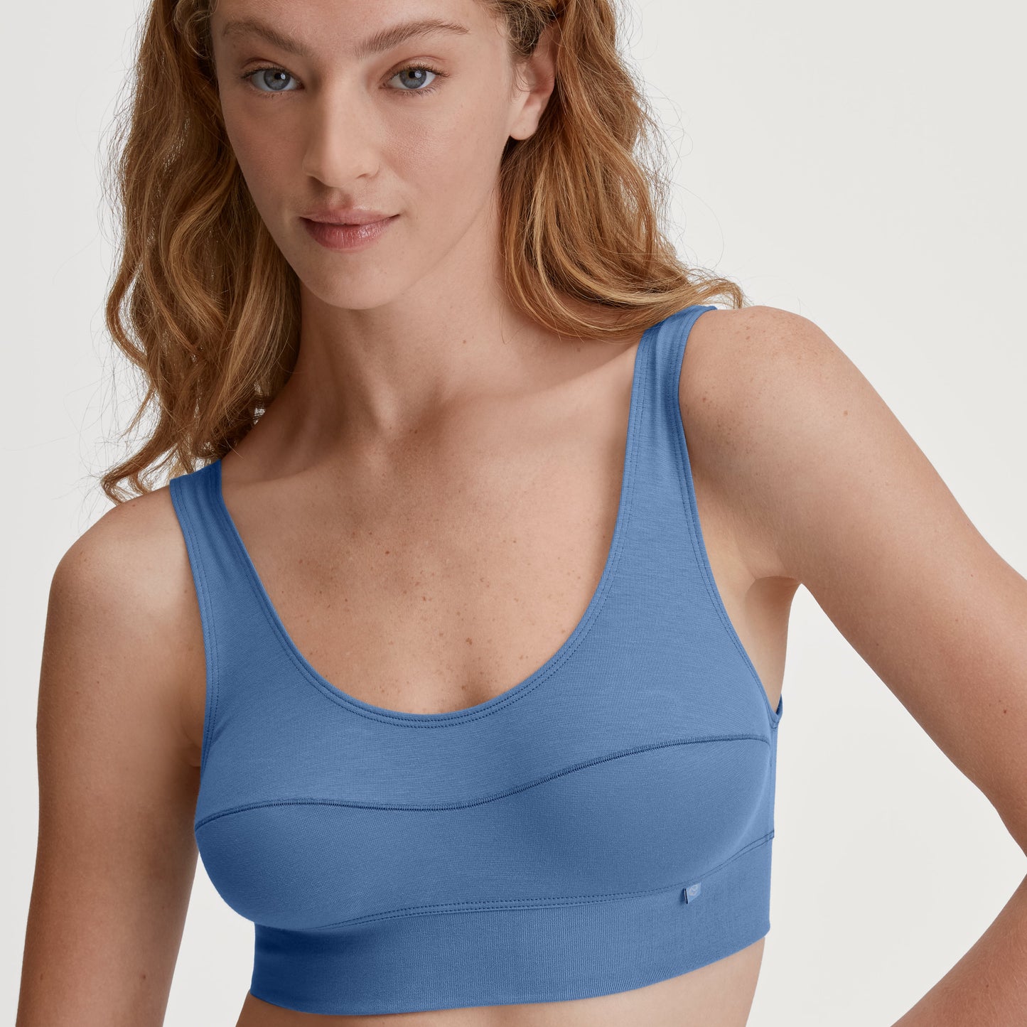 Woman wearing a blue sports bra against a plain background