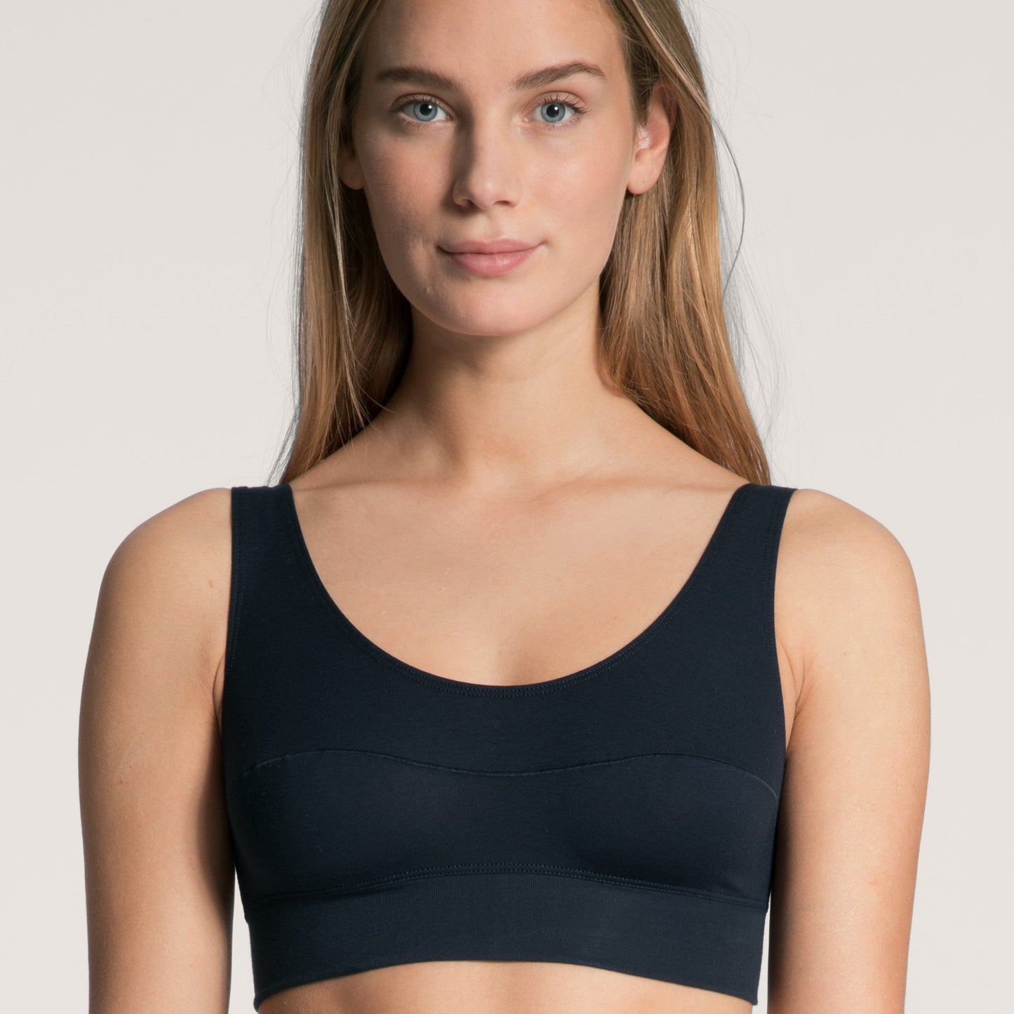 Two models, one in a white and one in a black bralette, posing on a neutral background.