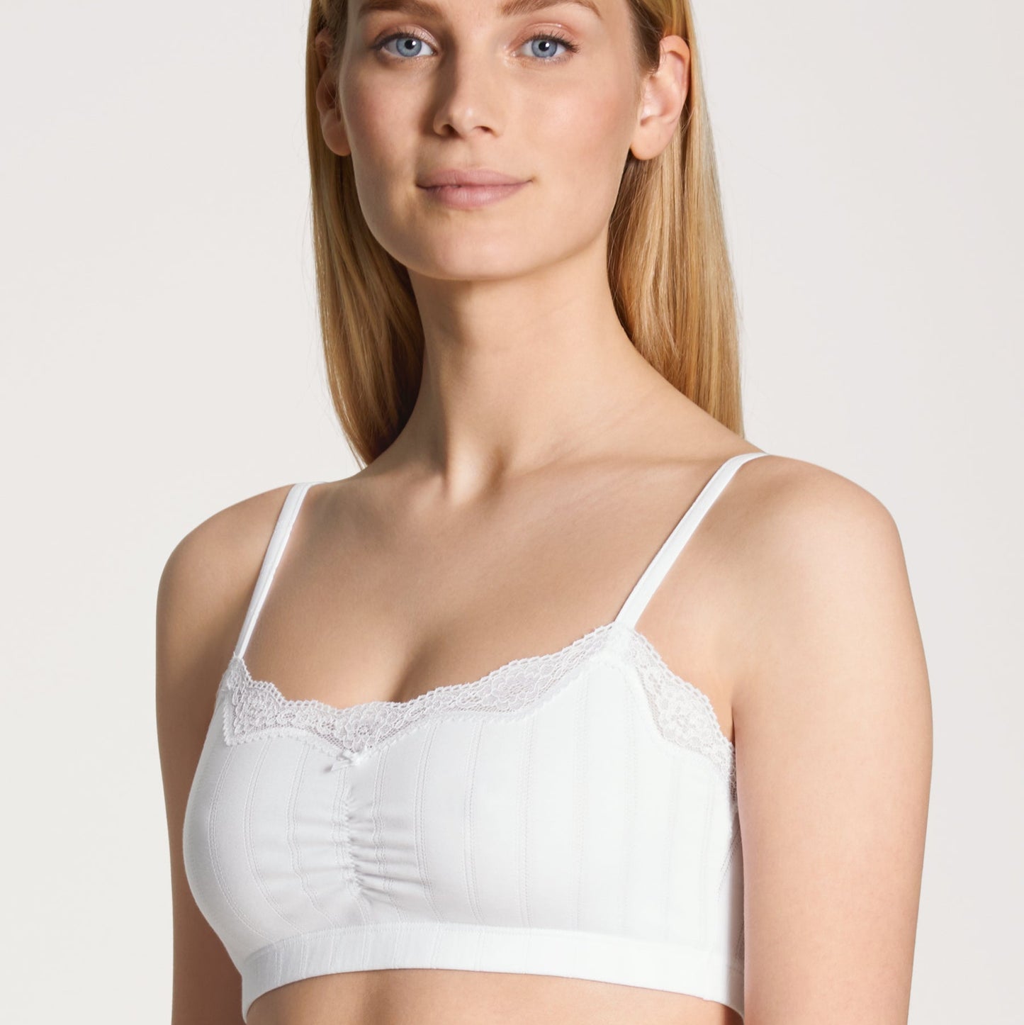 A woman wearing a white bralette with a jacquard look design.