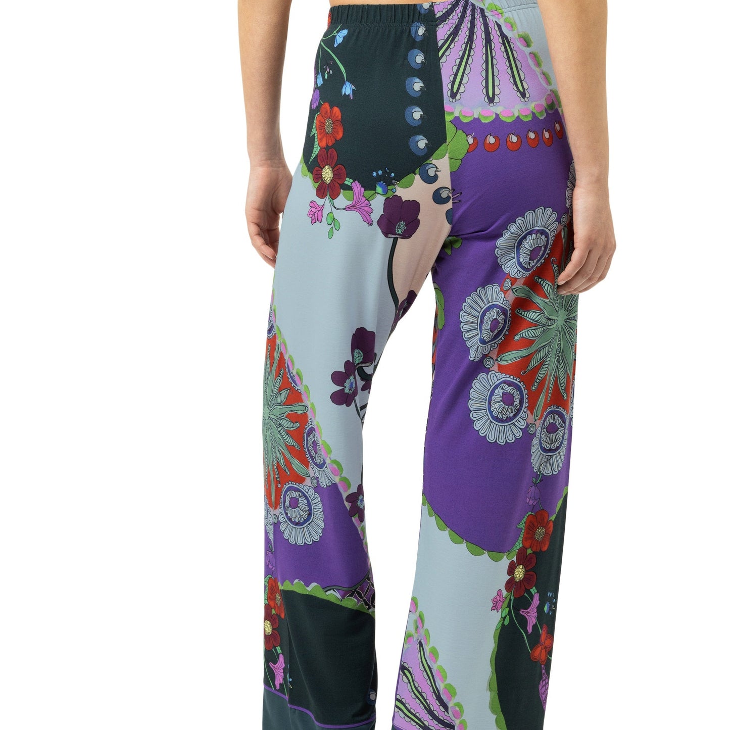 A model from the back wearing wide-leg pajama pants with a colorful patchwork bohemian floral print in purple, teal, green, and orange, paired with a purple bikini top against a white background.