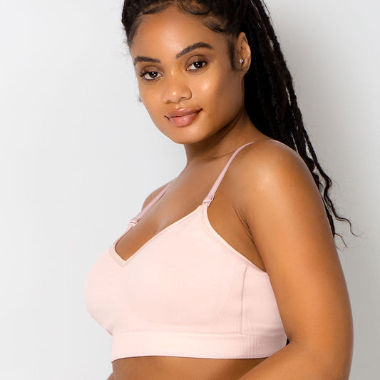 Woman wearing a light pink bralette against a plain background