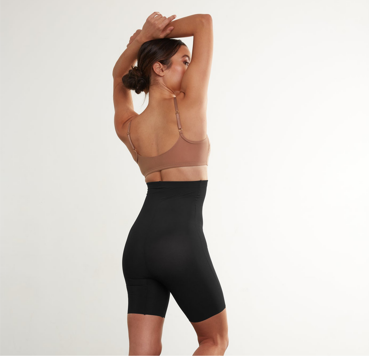 Woman wearing a brown bra and black shorts on a white background