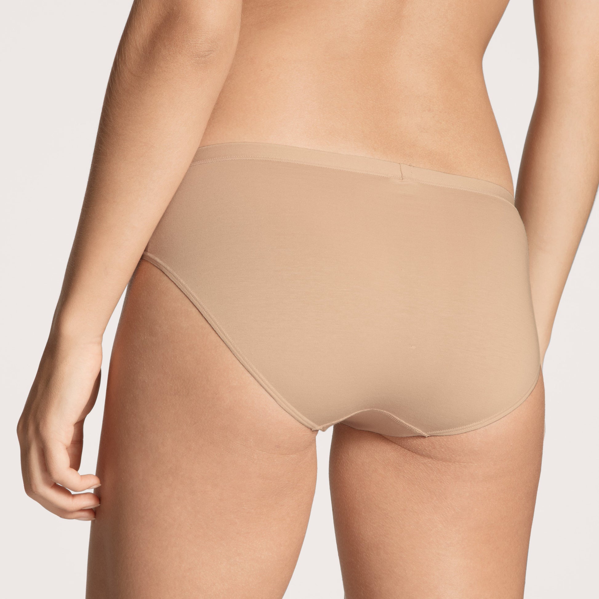 Beige underwear worn by a person on a plain background