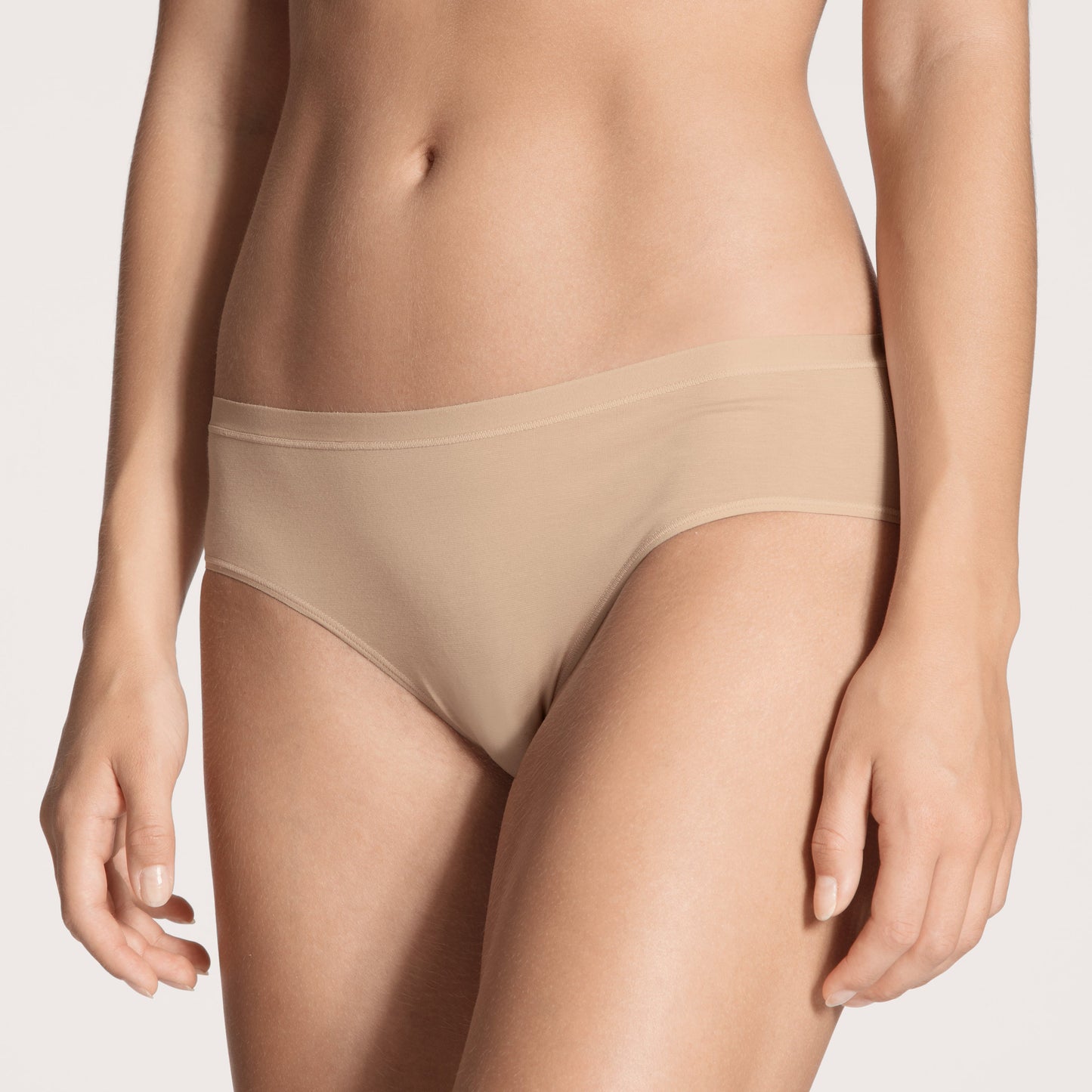 Beige underwear worn by a person on a plain background