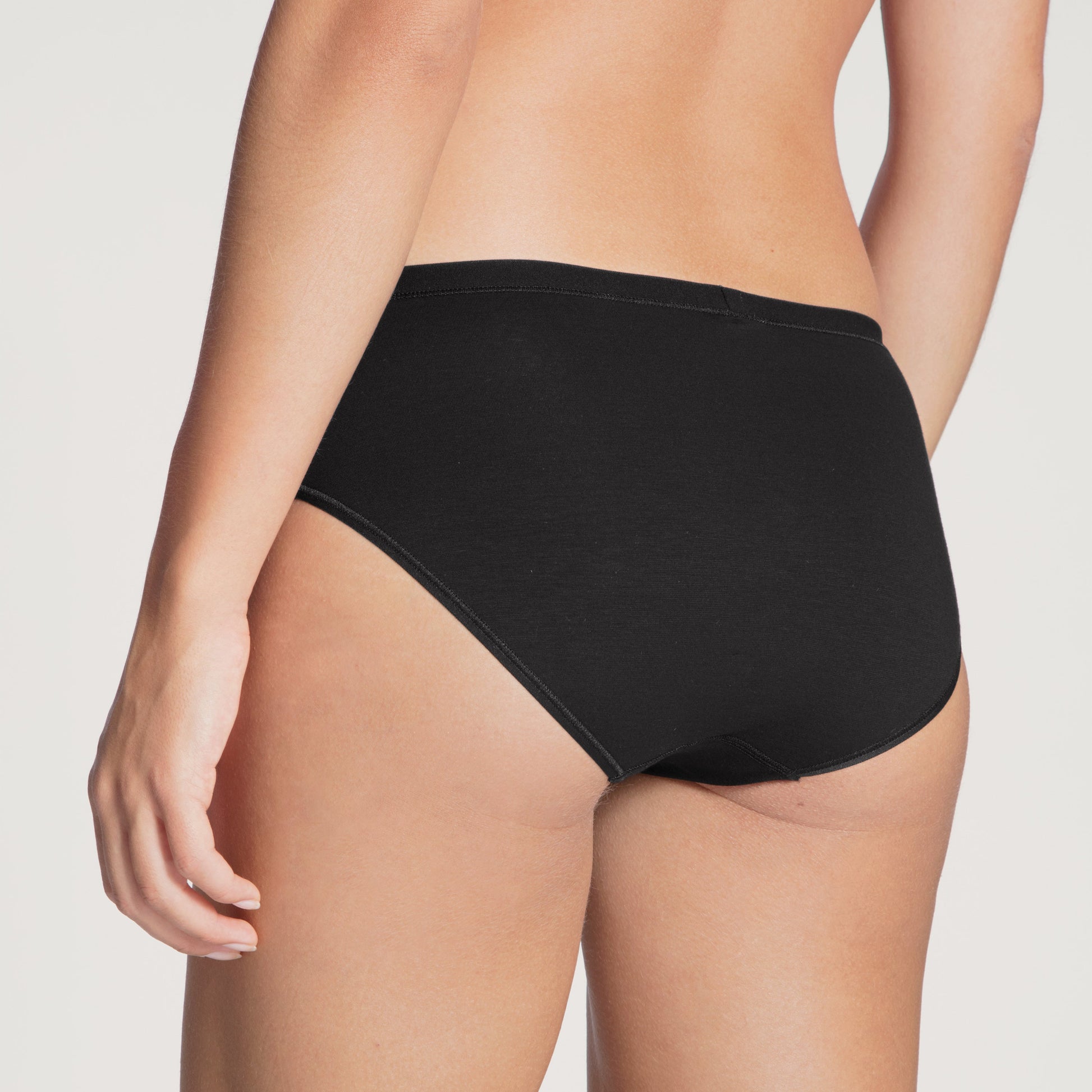 Person wearing black high-waisted underwear on a plain background