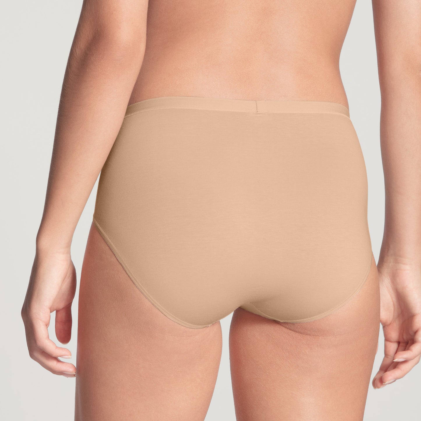 Beige underwear worn by a person on a plain background