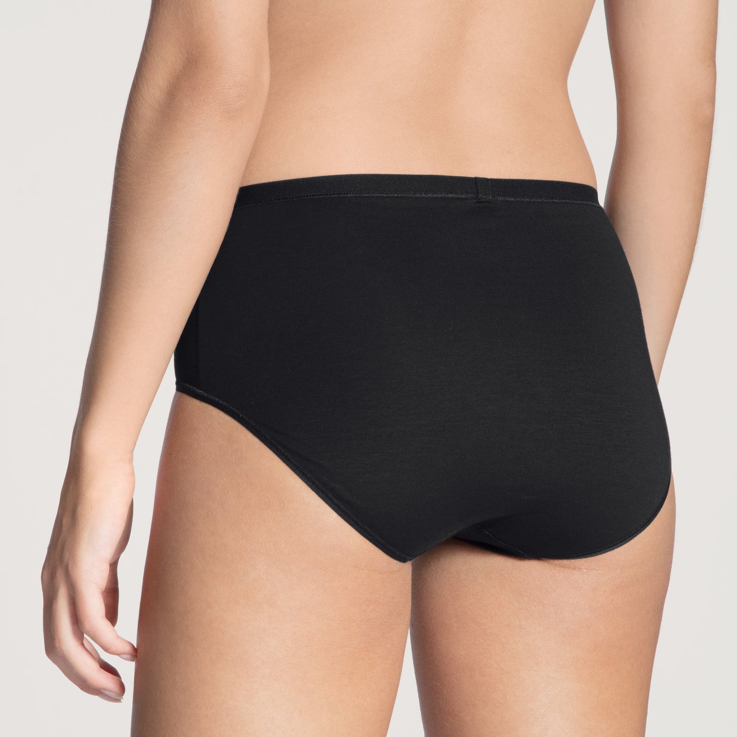 Black underwear worn by a person on a plain background