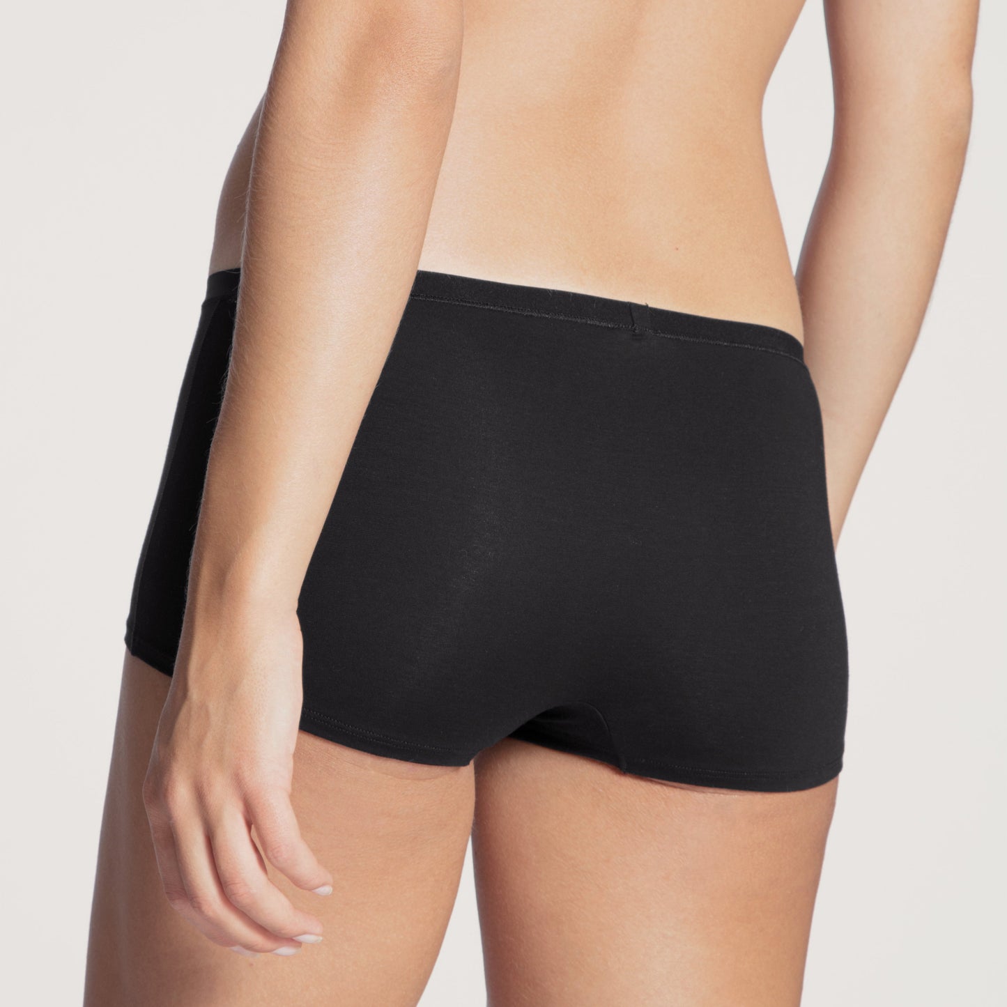 Person wearing black underwear on a plain background