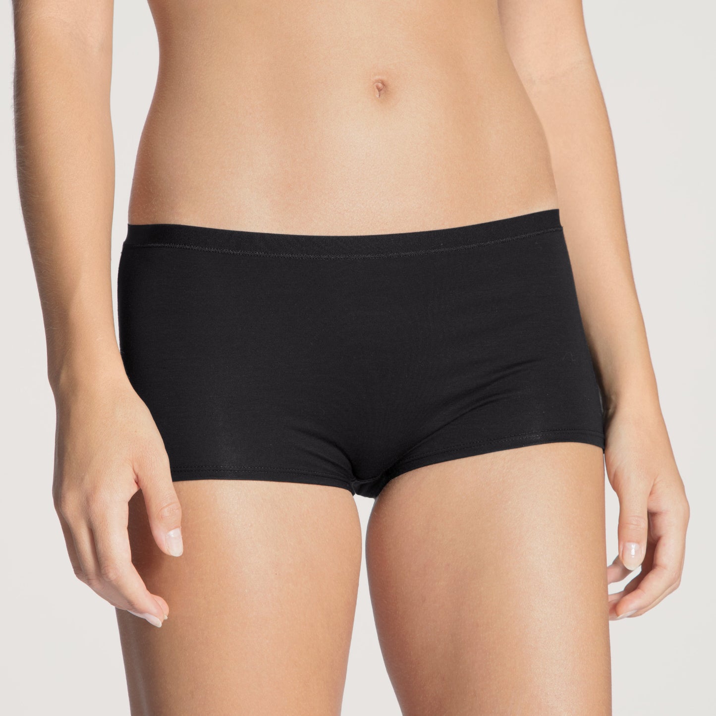 Black underwear worn by a person on a plain background