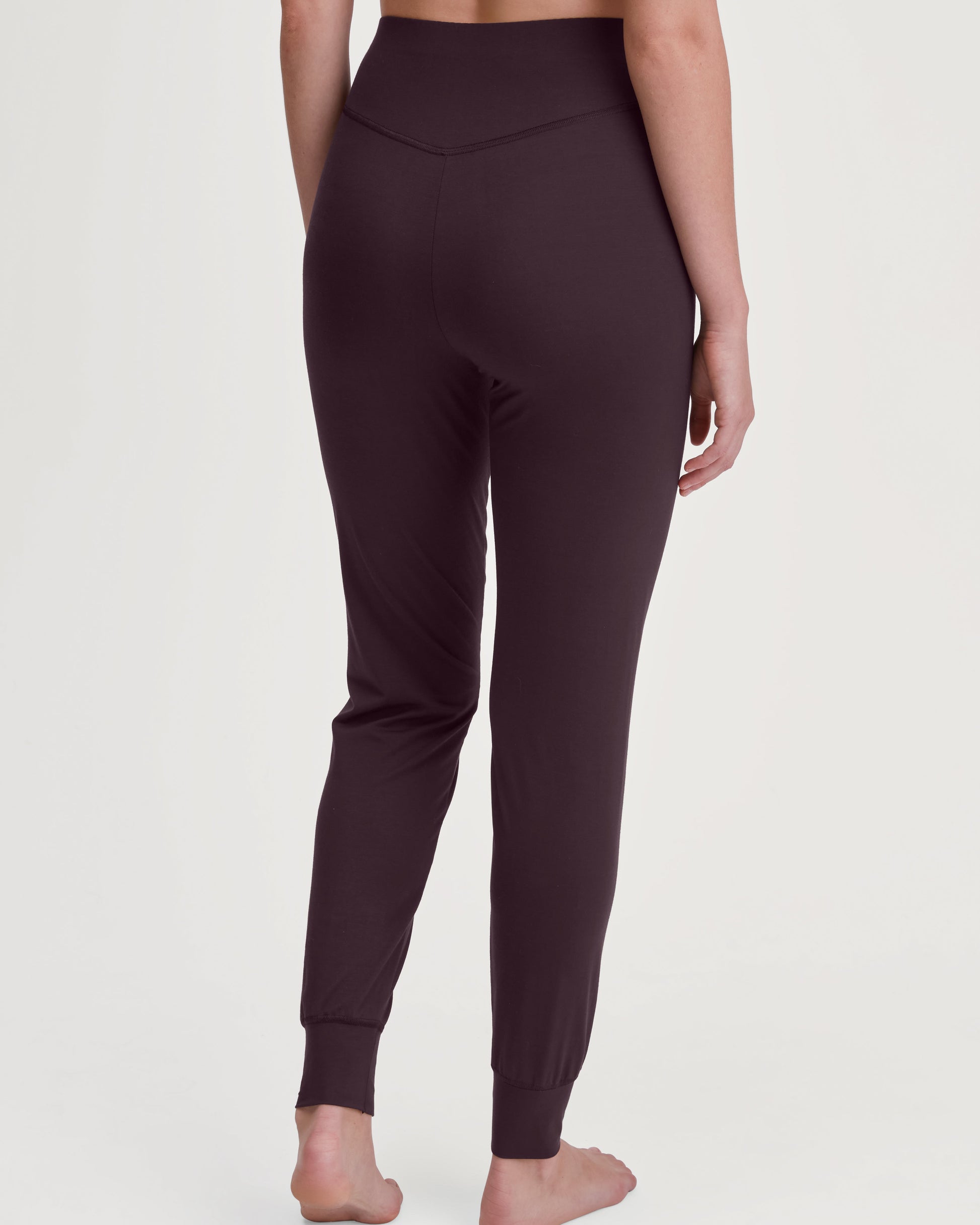 Dark plum leggings worn by a person on a white background