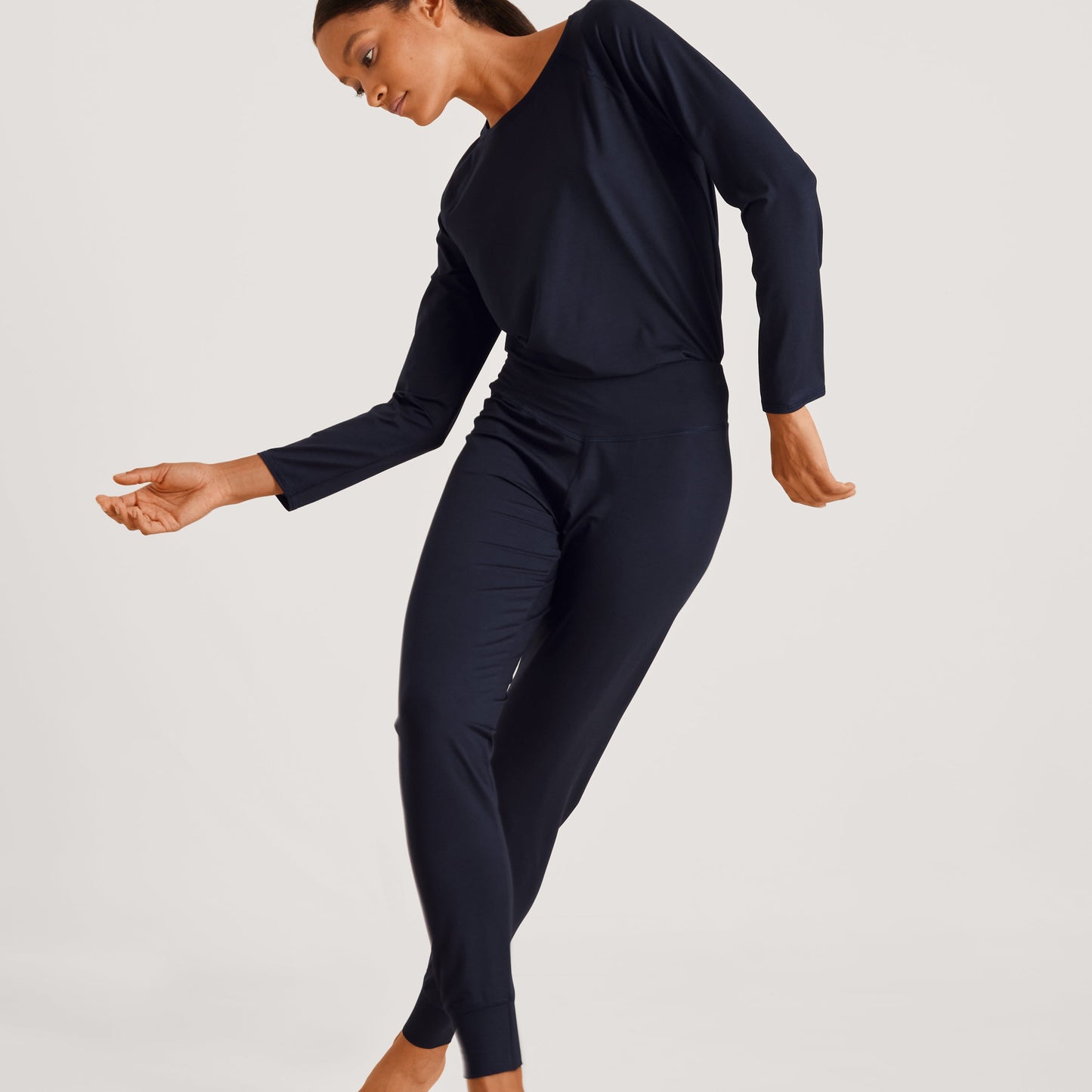 A person wearing navy-colored balancing pants, performing a dance move.