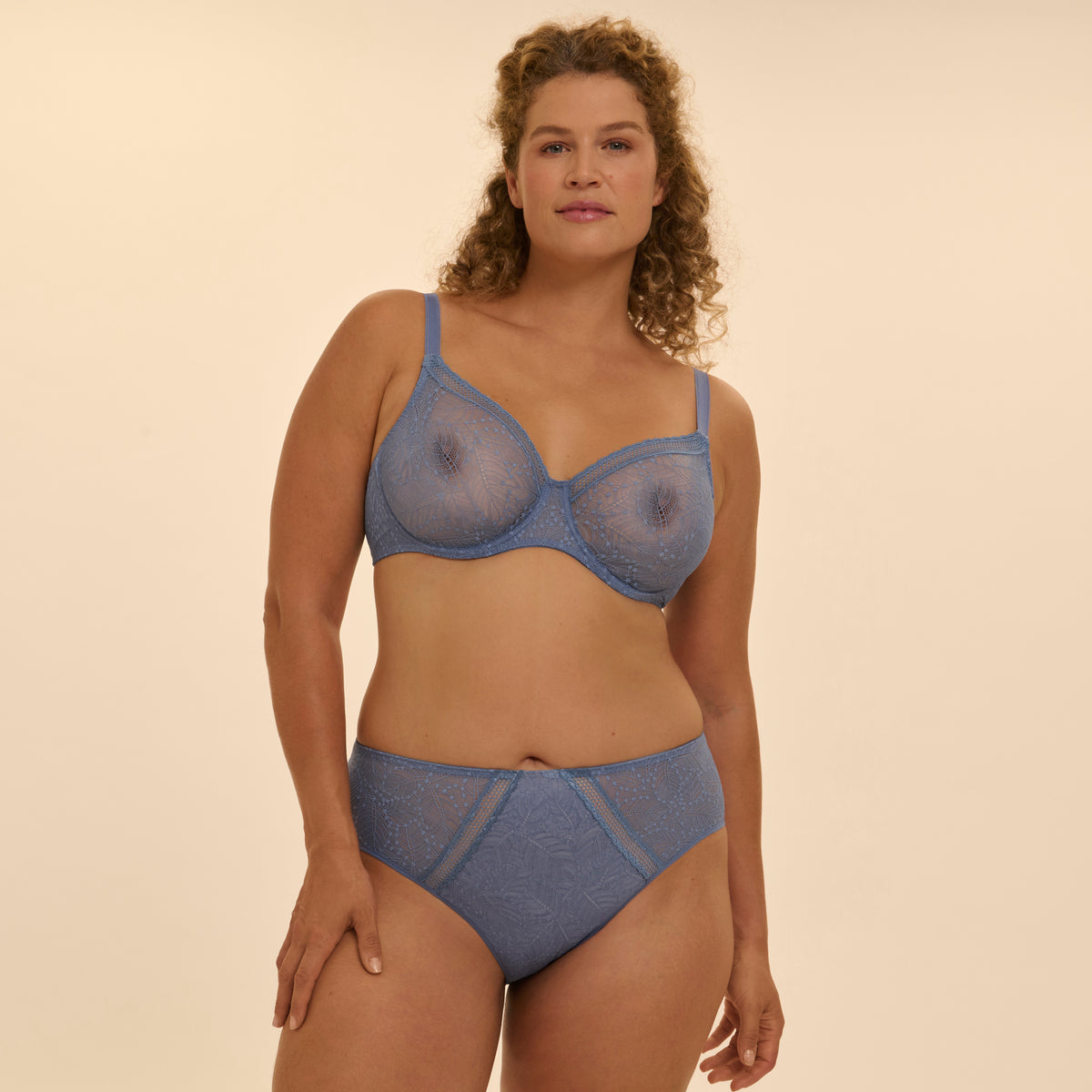 Woman wearing a blue bra and panties set against a beige background