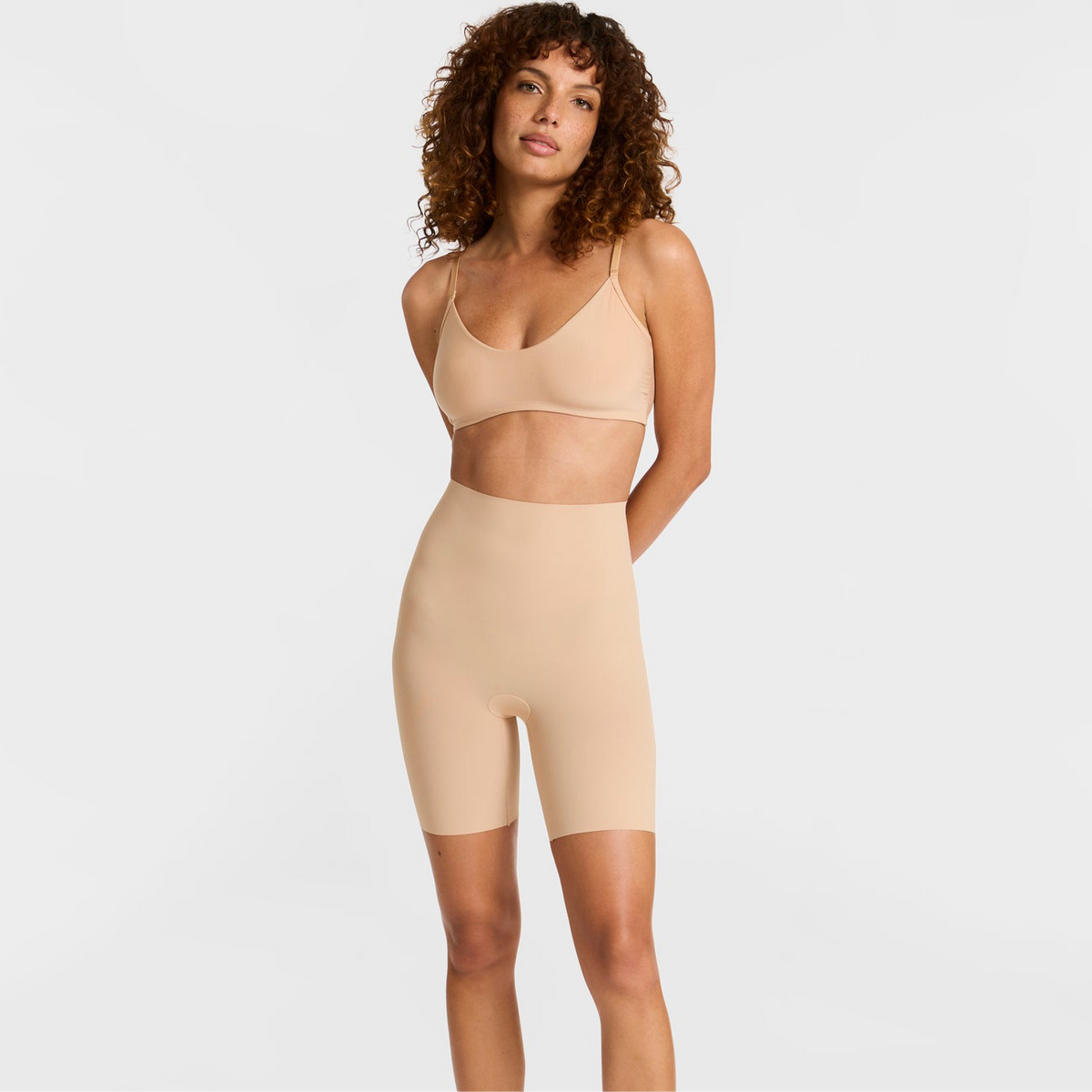 Woman wearing a beige shapewear outfit on a plain background
