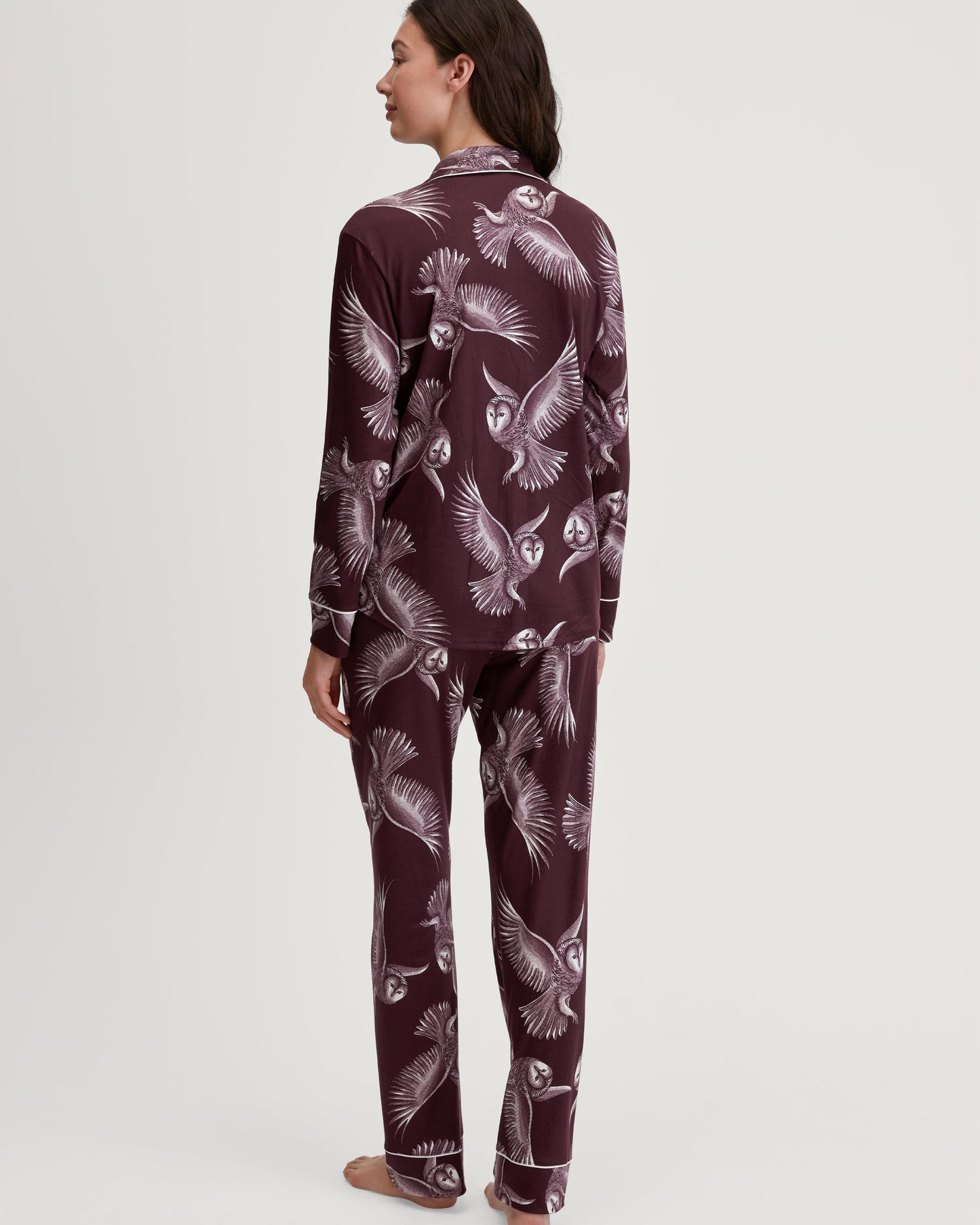Person wearing a maroon pajama set with a butterfly pattern on a white background