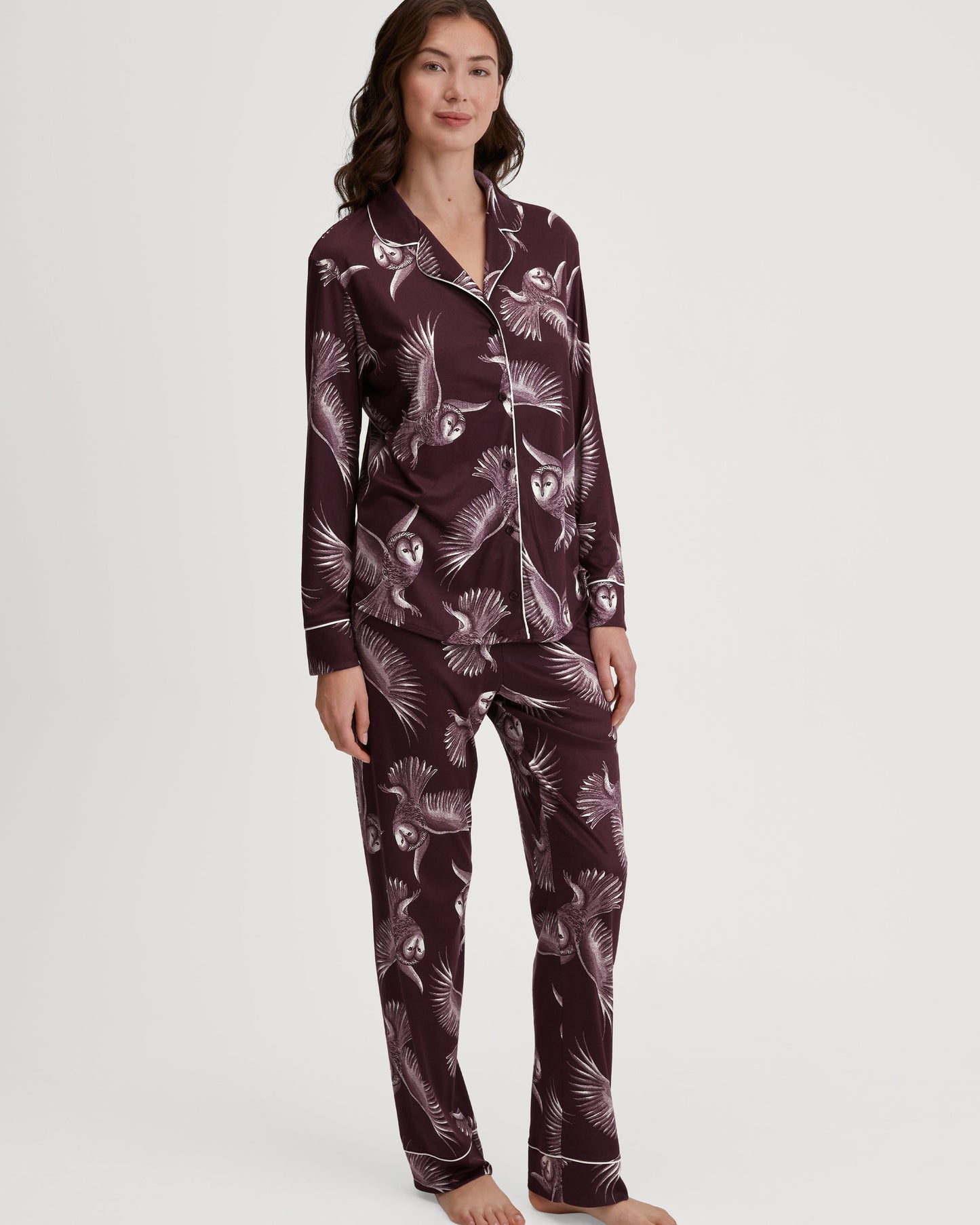 Woman wearing a dark purple pajama set with a pattern on a white background