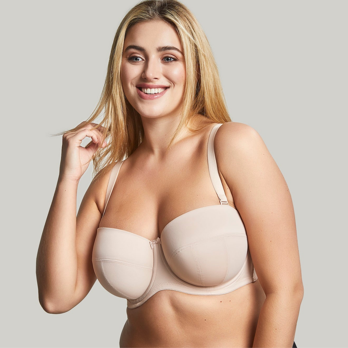 Woman wearing a beige bra against a plain background