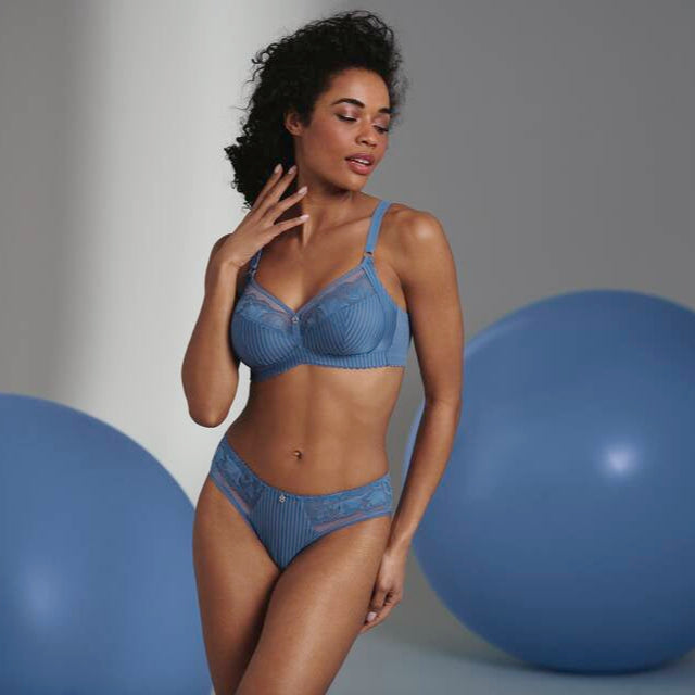 A woman wearing a blue striped soft bra with floral lace details on the upper cup.
