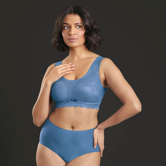 A woman wearing a blue lace bralette and matching high-waisted briefs.