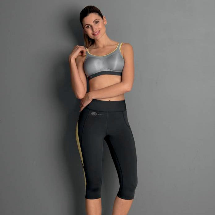 A woman wearing a gray Momentum sports bra with a round neckline and matching black sports leggings.