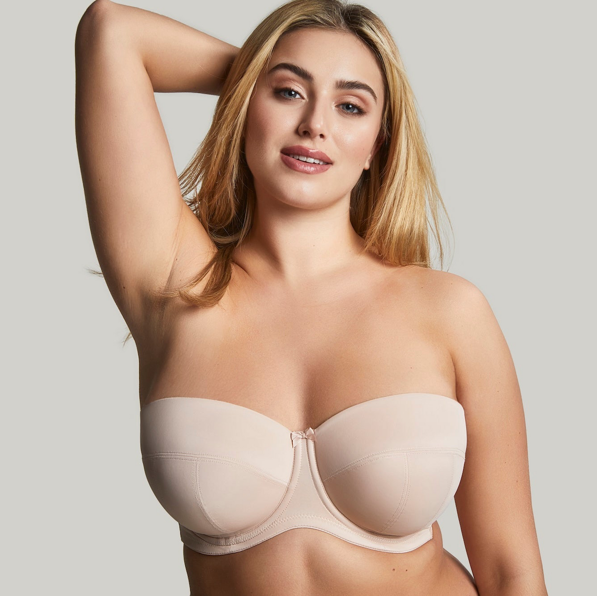 Woman wearing a beige strapless bra against a plain background