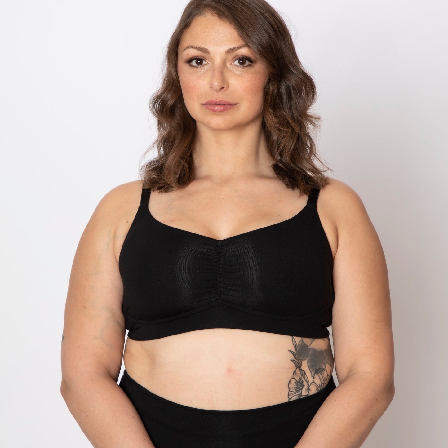 Woman wearing a black bra and high-waisted black underwear on a white background