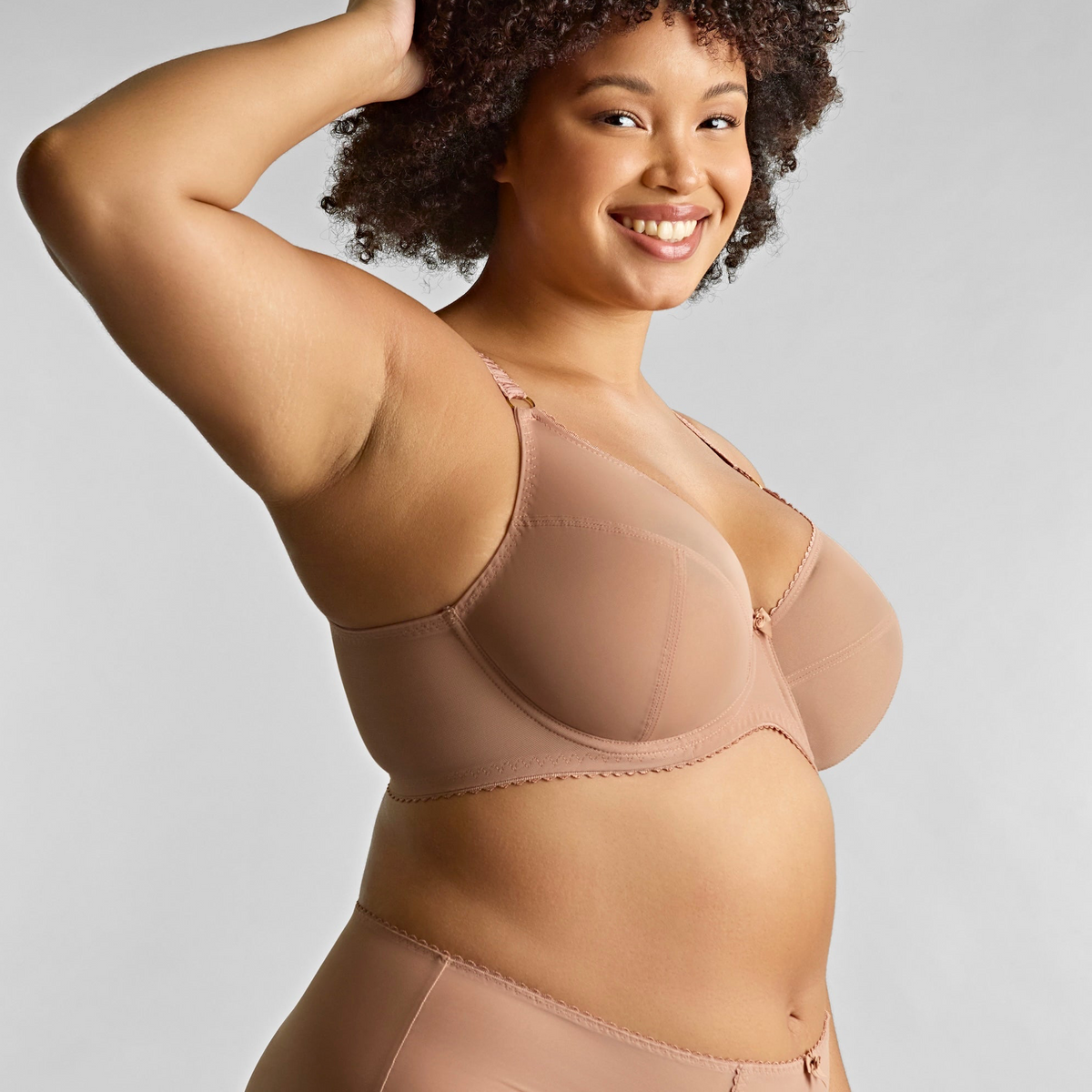Woman wearing a beige shapewear garment against a plain background
