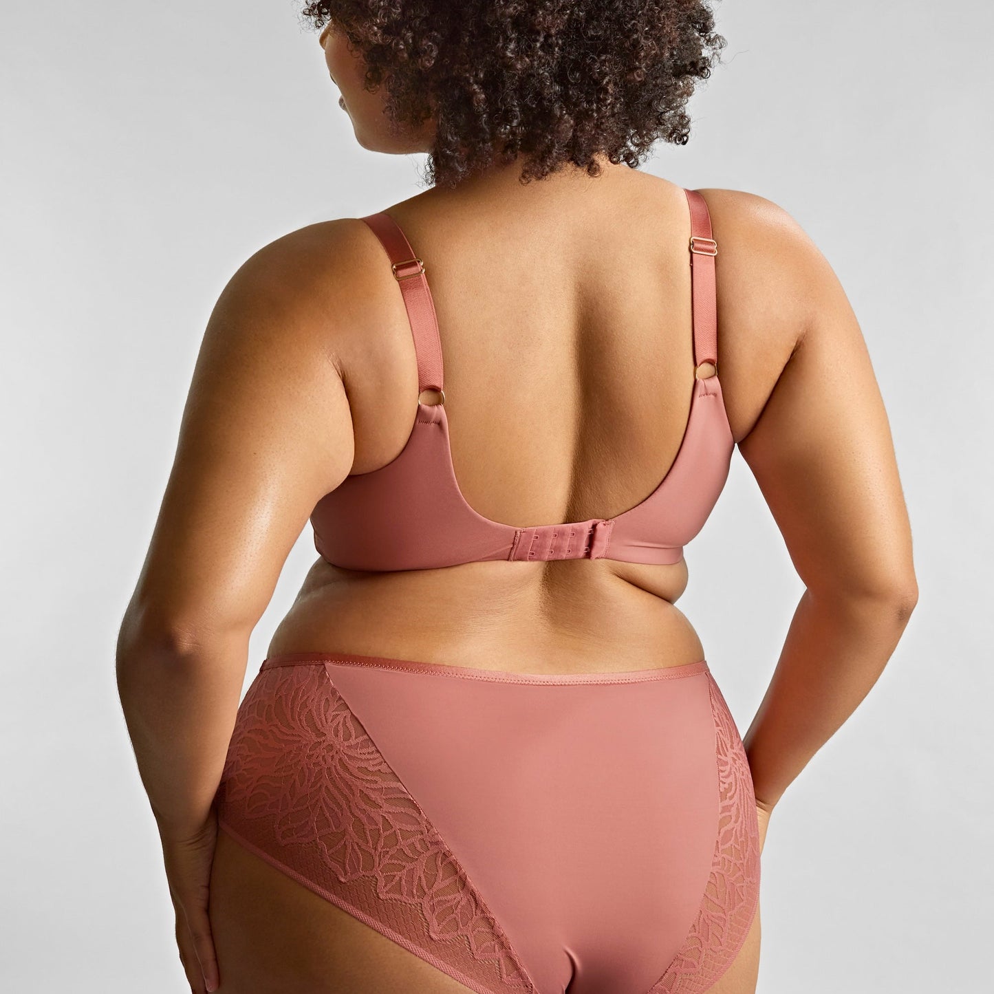 Person wearing a pink lingerie set against a plain background