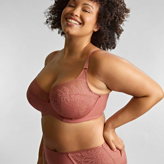 Woman wearing a pink lingerie set against a plain background