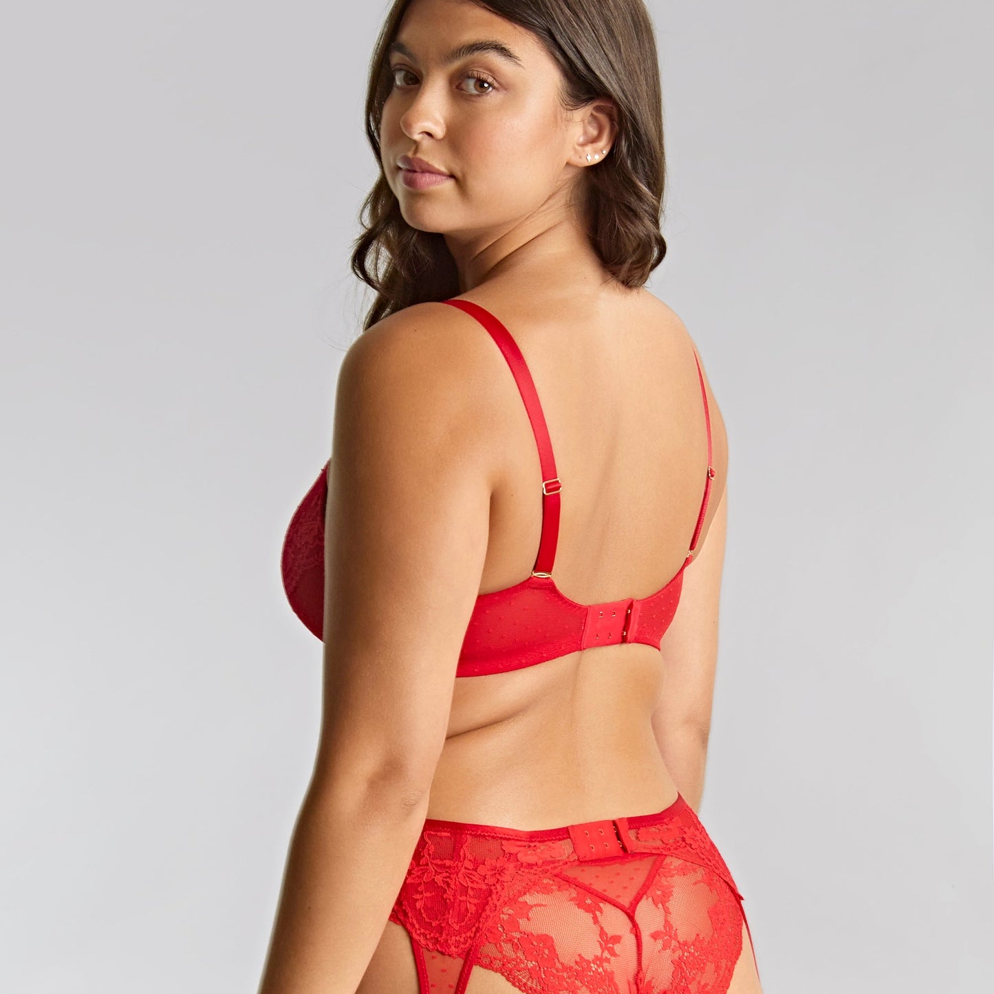 Woman wearing a red lingerie set with a plain background