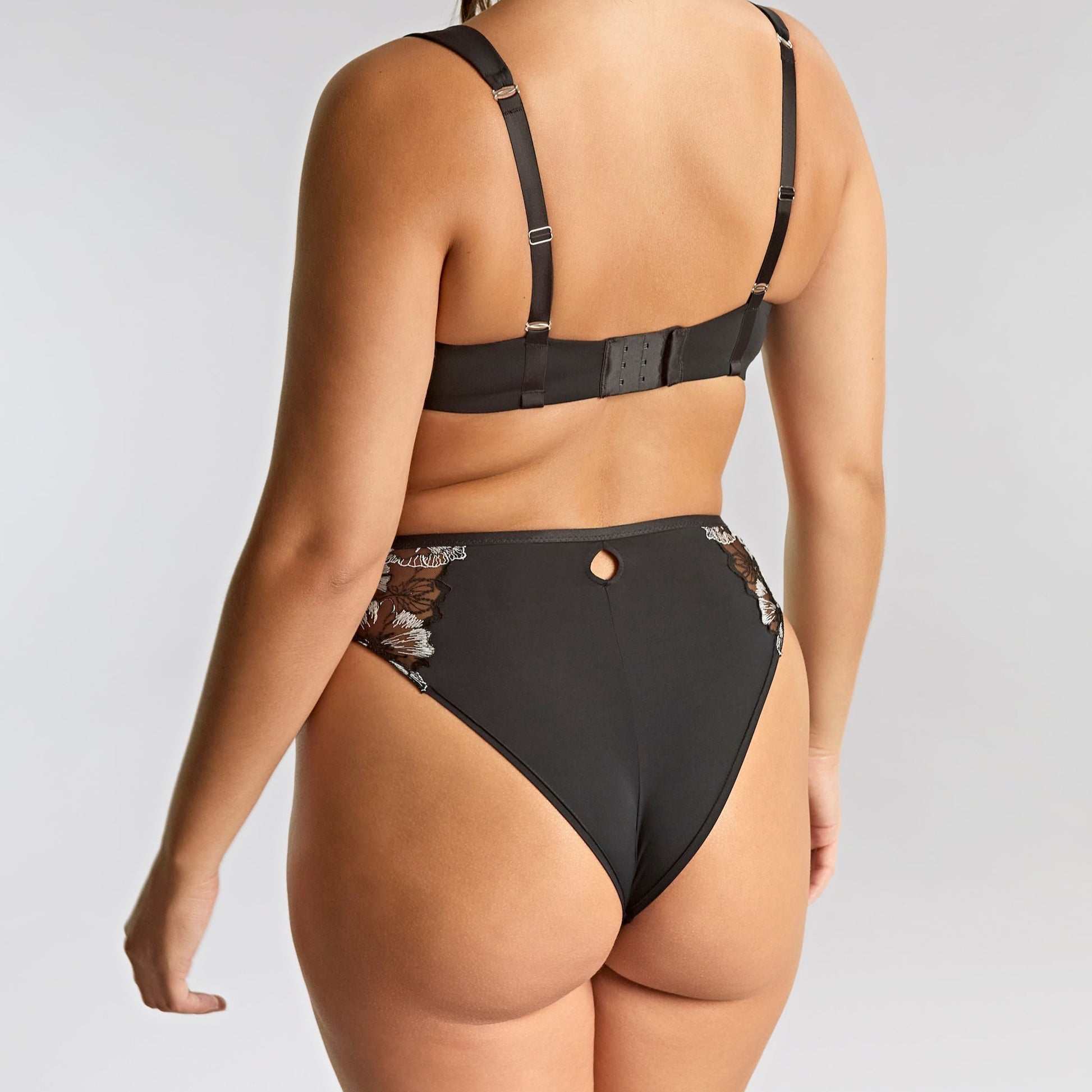 Woman wearing a black bikini with a plain background