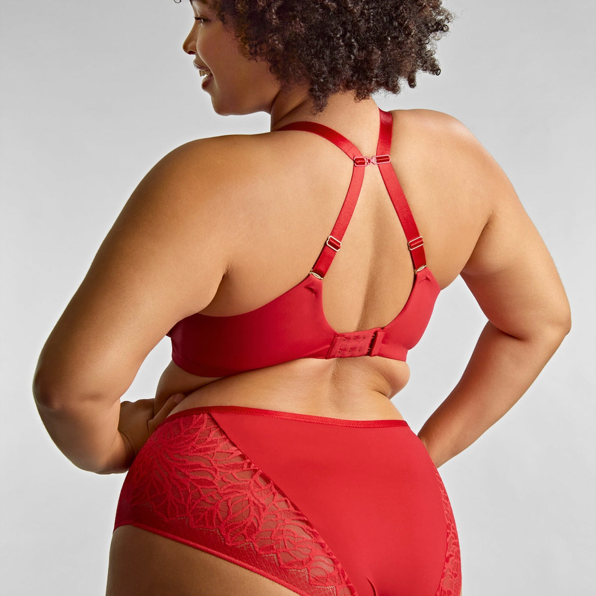 Person wearing a red lingerie set with a plain background