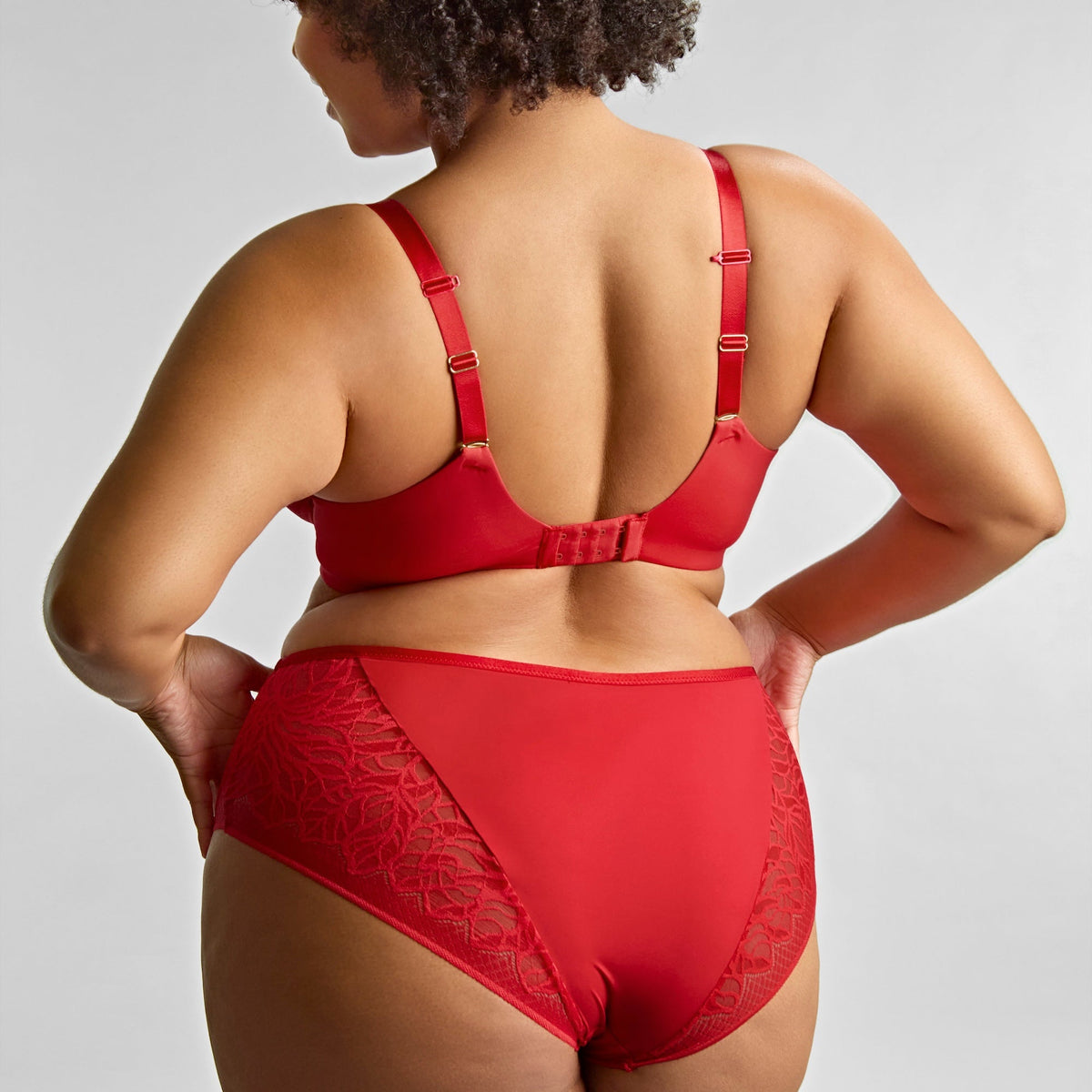 Person wearing a red lingerie set on a plain background