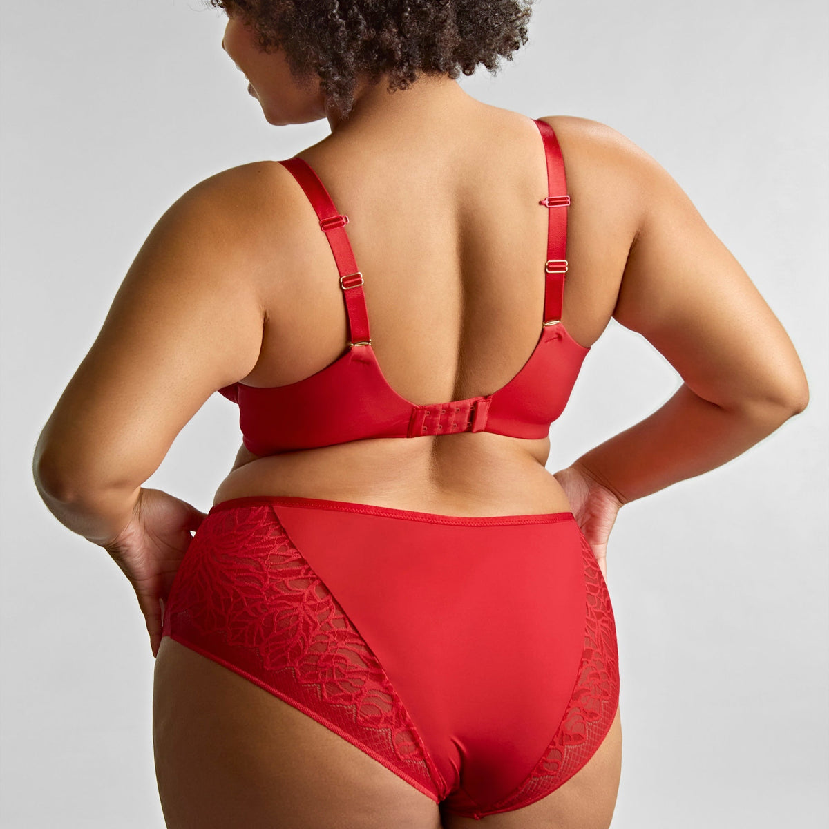 Person wearing a red lingerie set on a plain background