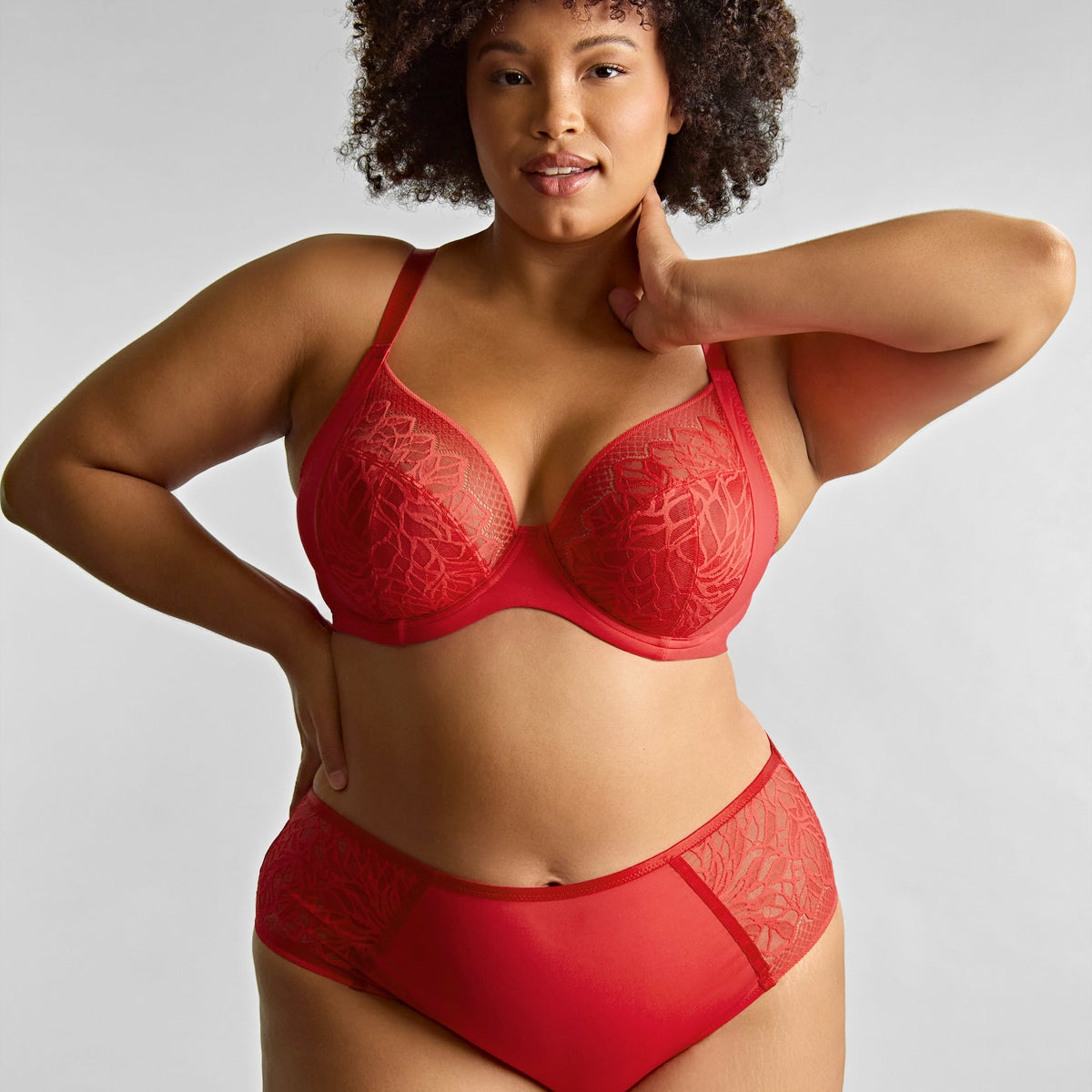 Woman wearing a red lingerie set against a plain background