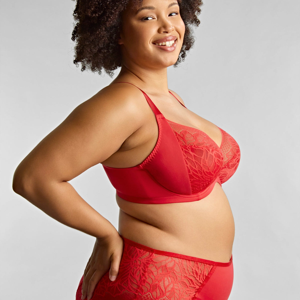 Woman wearing a red lace lingerie set against a plain background