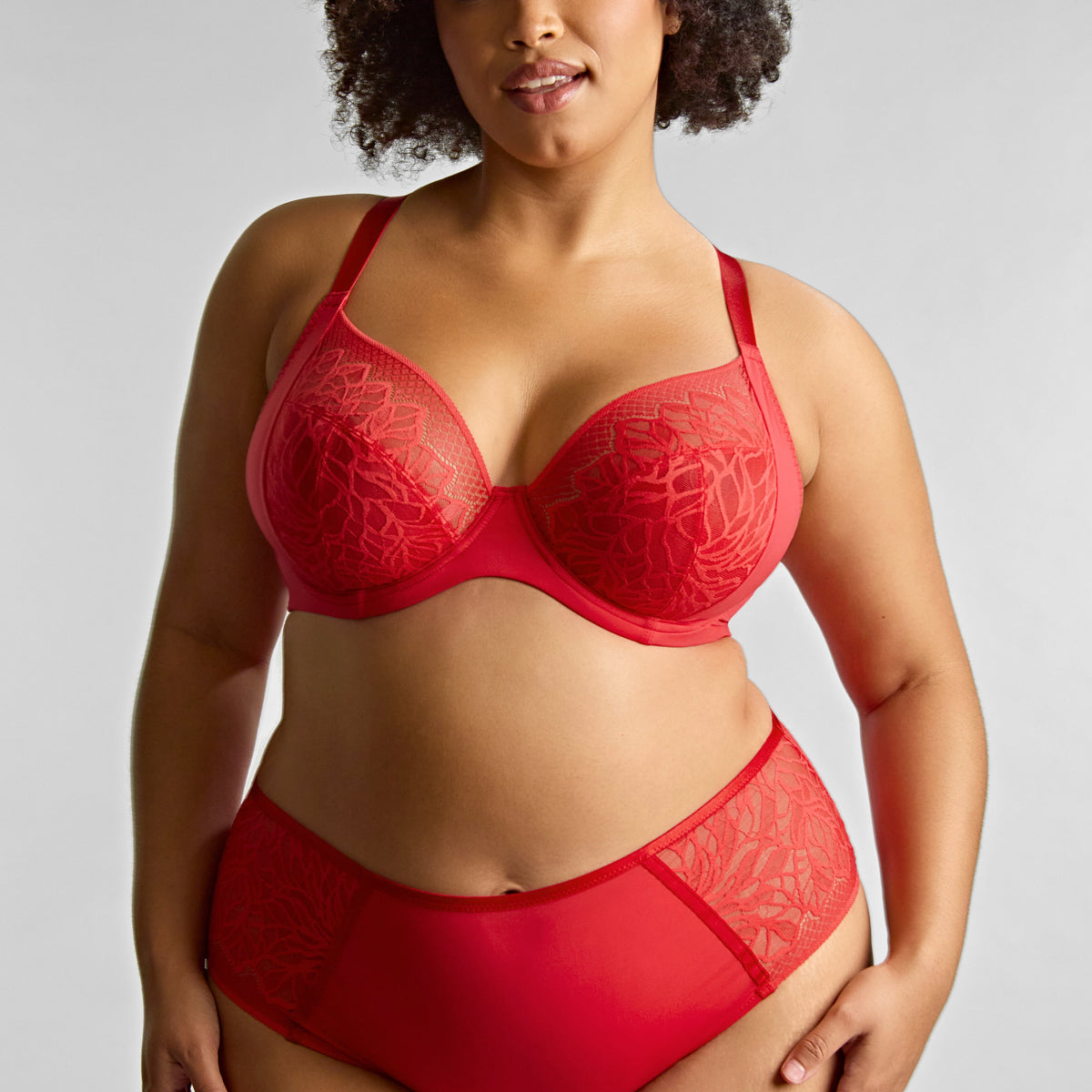 Woman wearing a red lingerie set against a plain background