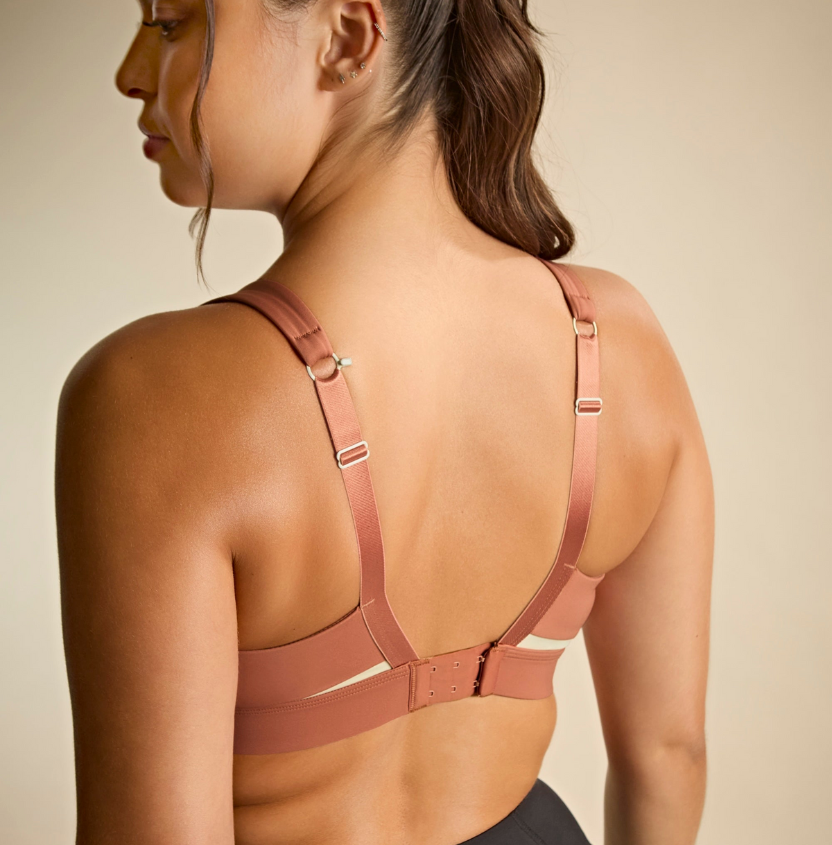 Woman wearing a pink sports bra against a beige background
