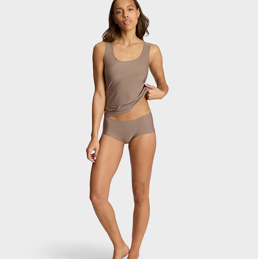 A woman modeling a matching two-piece lounge set in a solid taupe-brown color, consisting of a sleeveless tank top and high-waisted briefs, against a light gray studio background.
