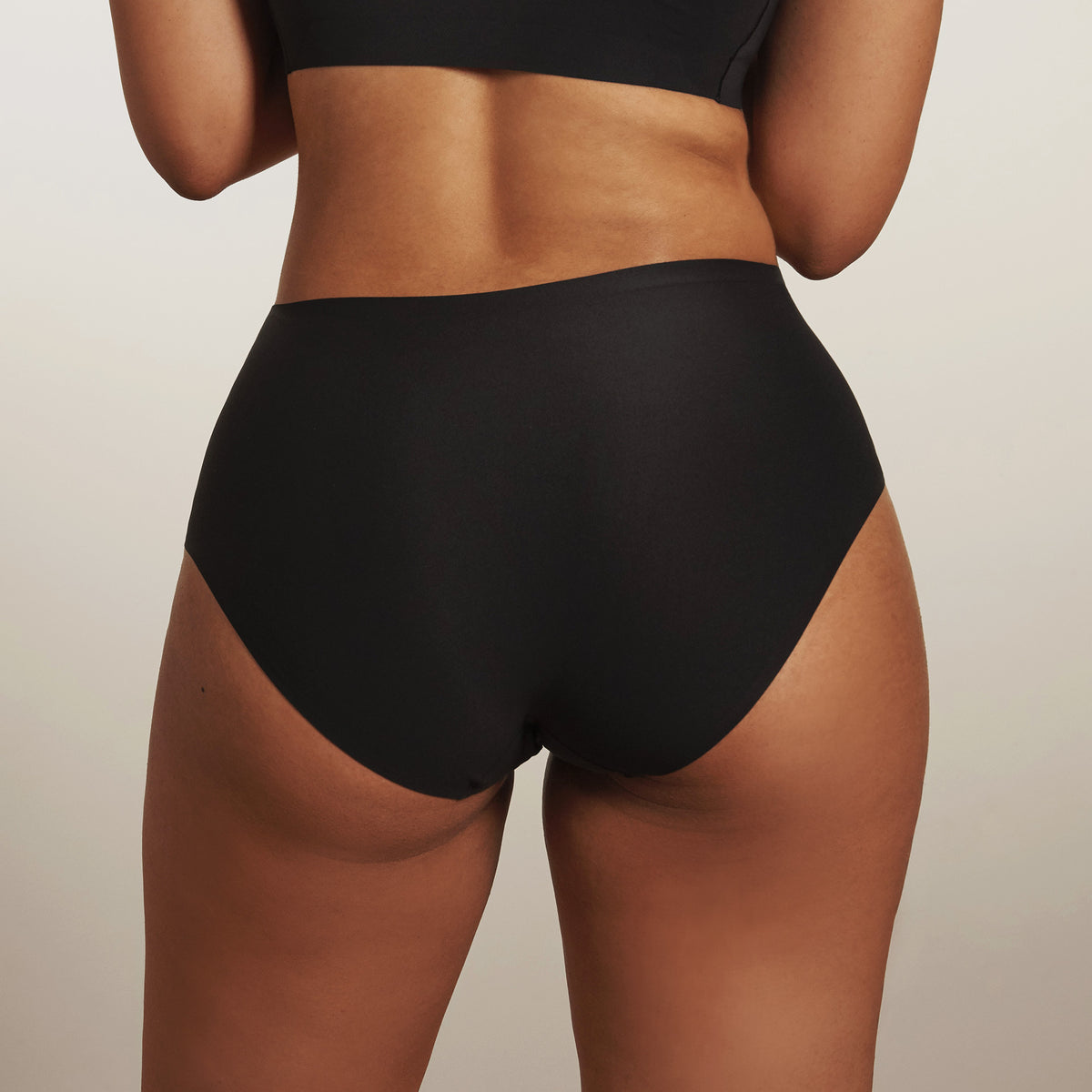 Person wearing black high-waisted underwear against a neutral background