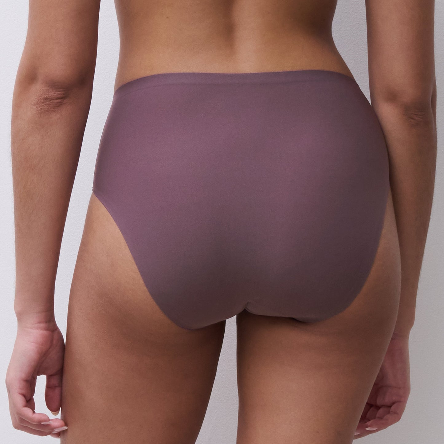 Rear view of a model wearing high-waisted, seamless underwear in a muted mauve-purple color, shown against a plain light gray background.