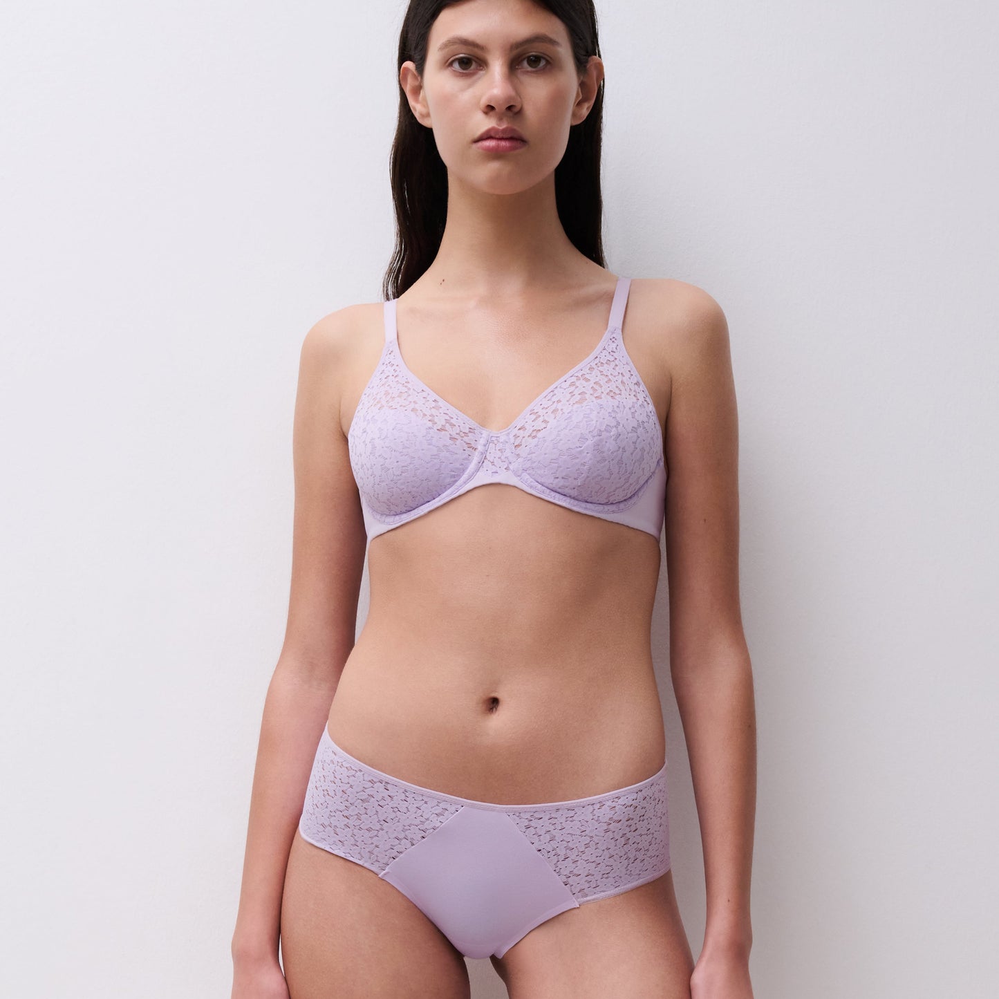 Woman wearing a light purple bra and underwear set against a plain background