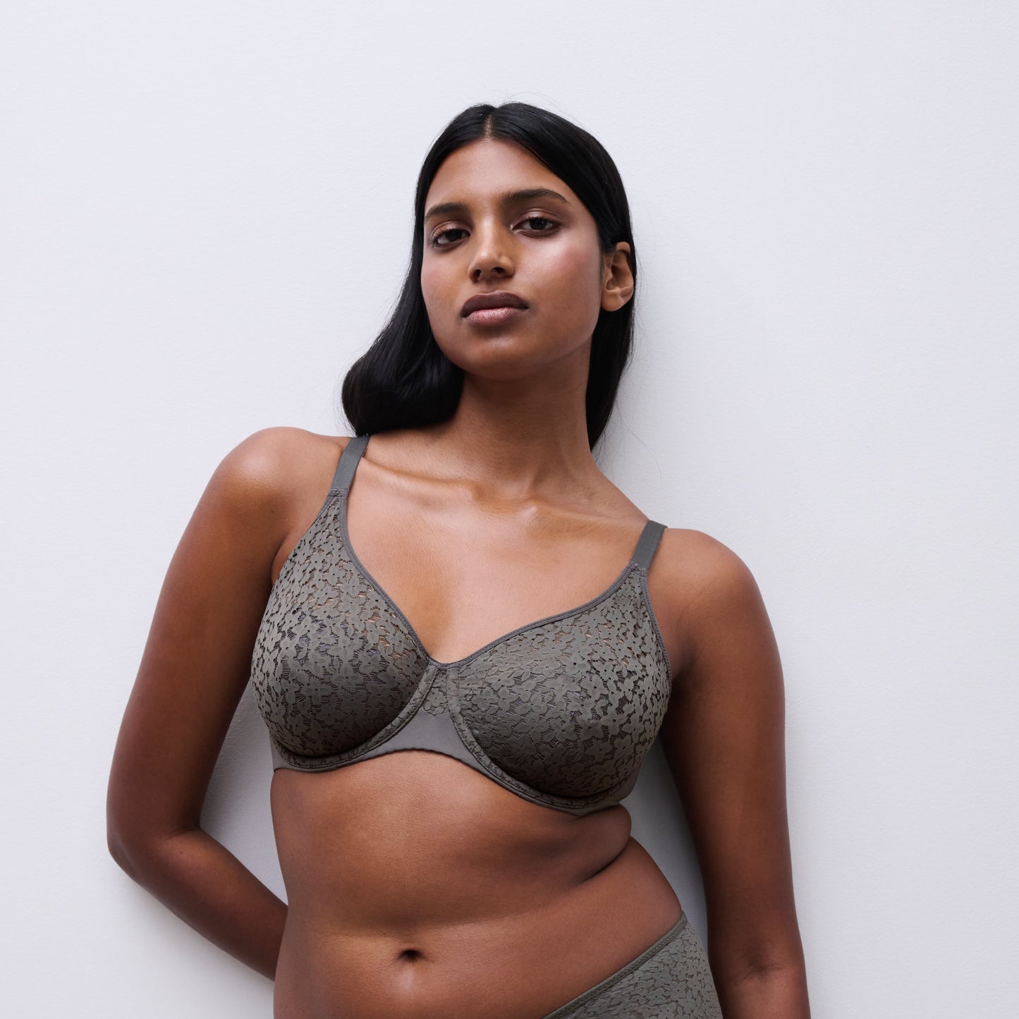 Woman wearing a green bra and panties set against a white background