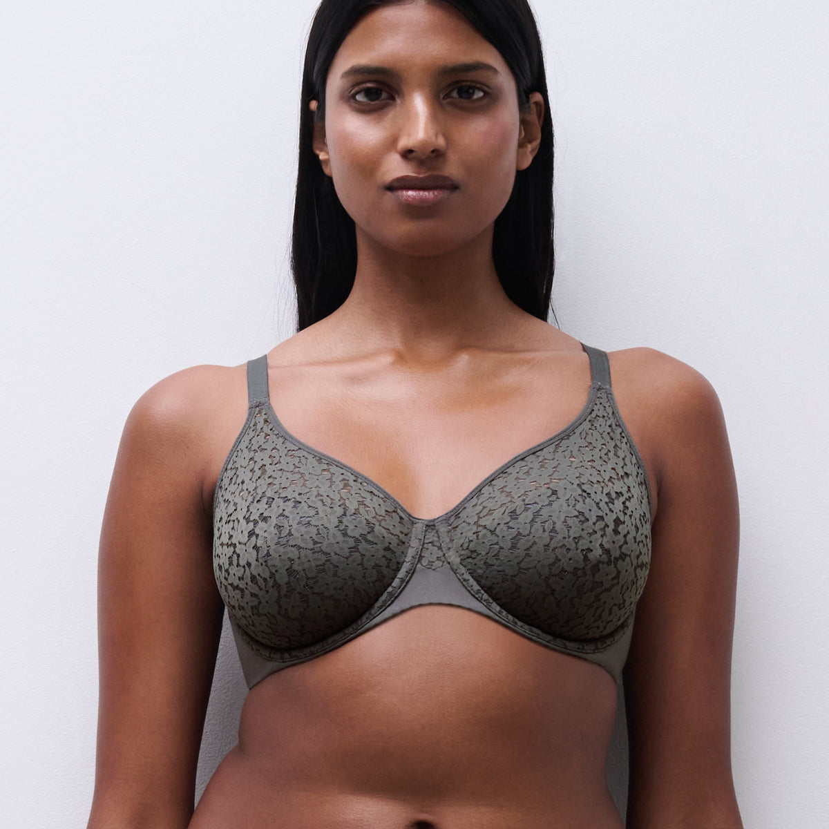 Woman wearing a gray patterned bra against a white background