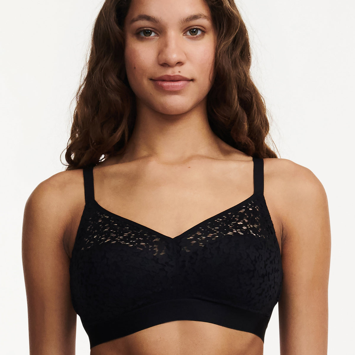A wirefree, black bra with a supportive and seamed construction, modeled by a woman.
