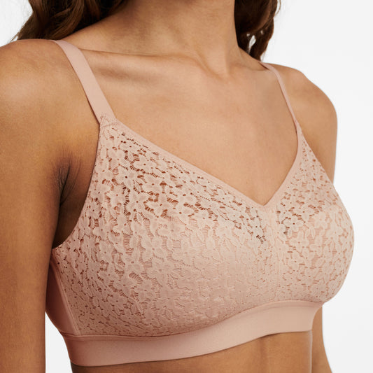 A wirefree, supportive bra in a nude blush color with a floral lace pattern.