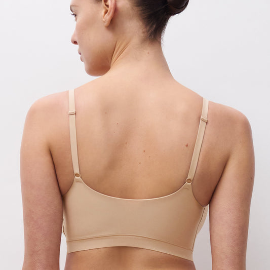 Woman wearing a beige bra against a plain background