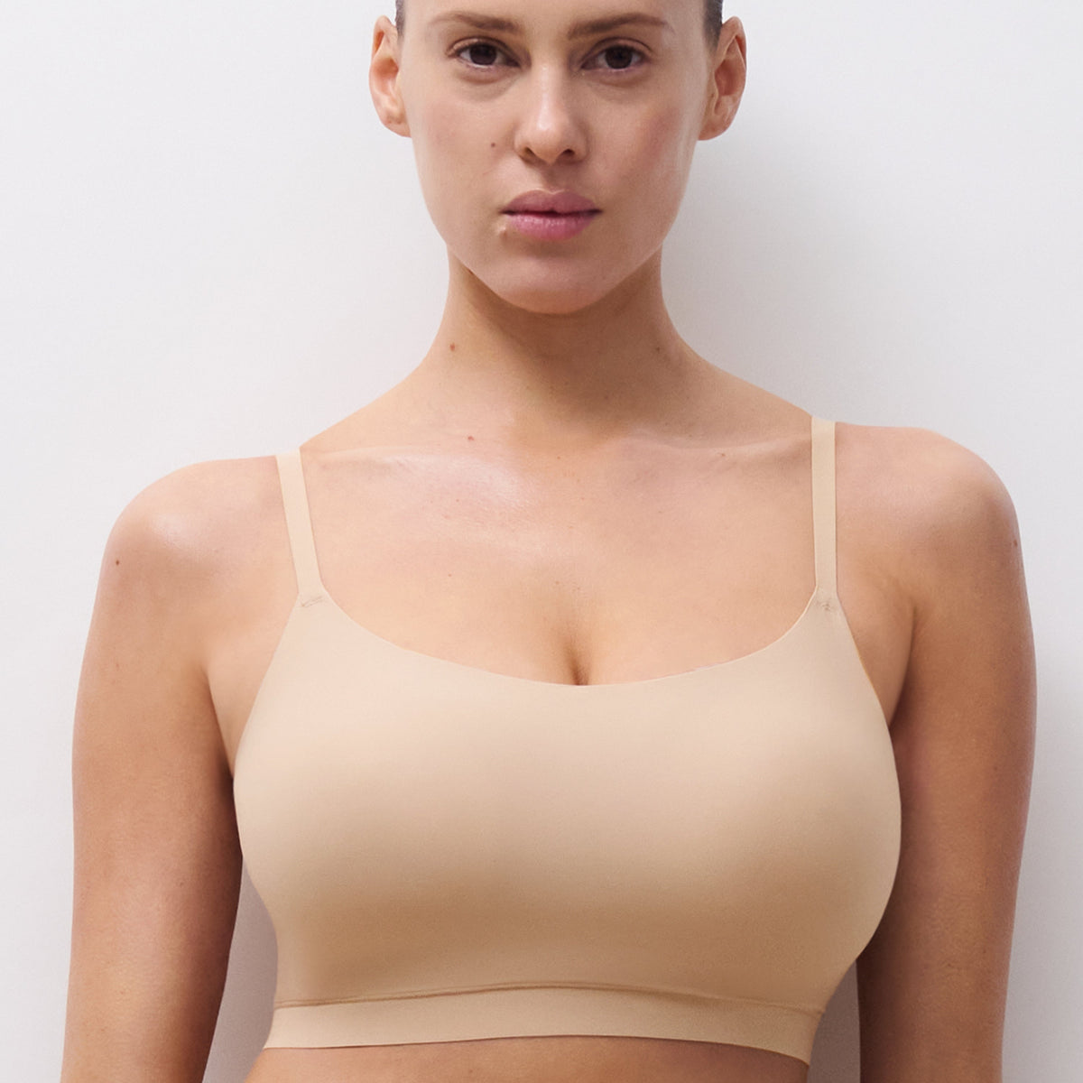 Woman wearing a beige bra against a plain background