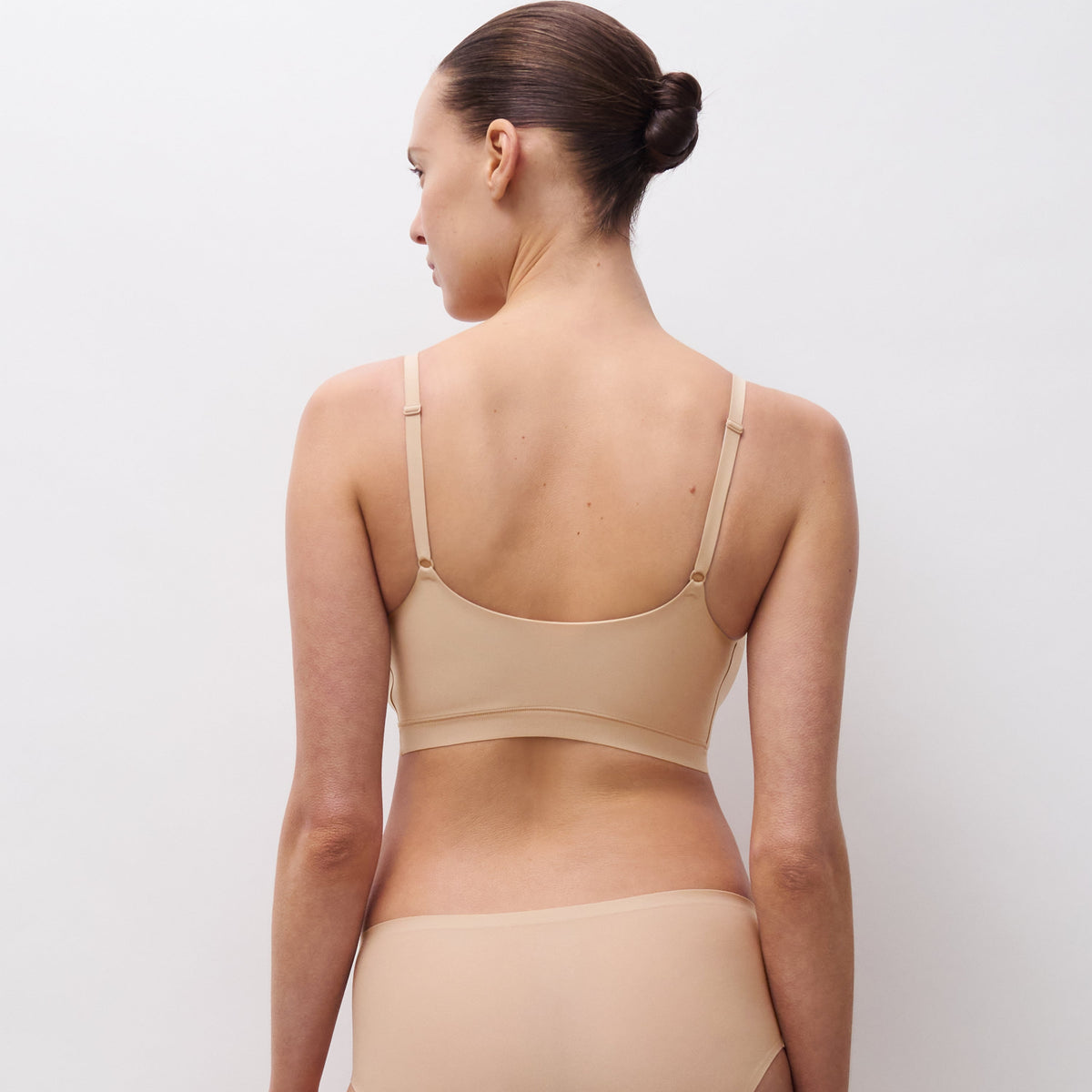 Woman wearing a beige bikini set on a plain background